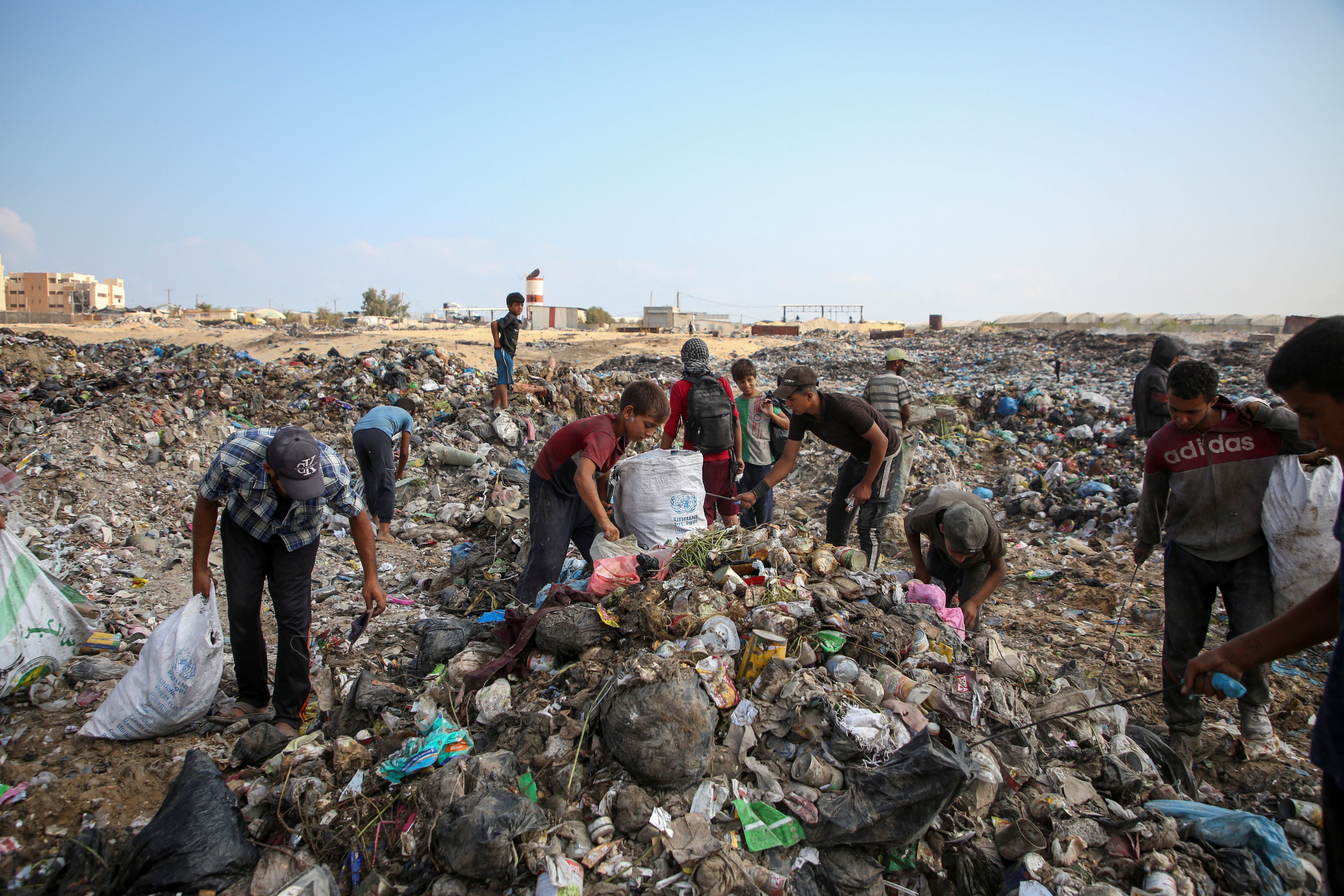 Displaced Palestinians scavange for usable items at a rubbish dump in Khan Younis