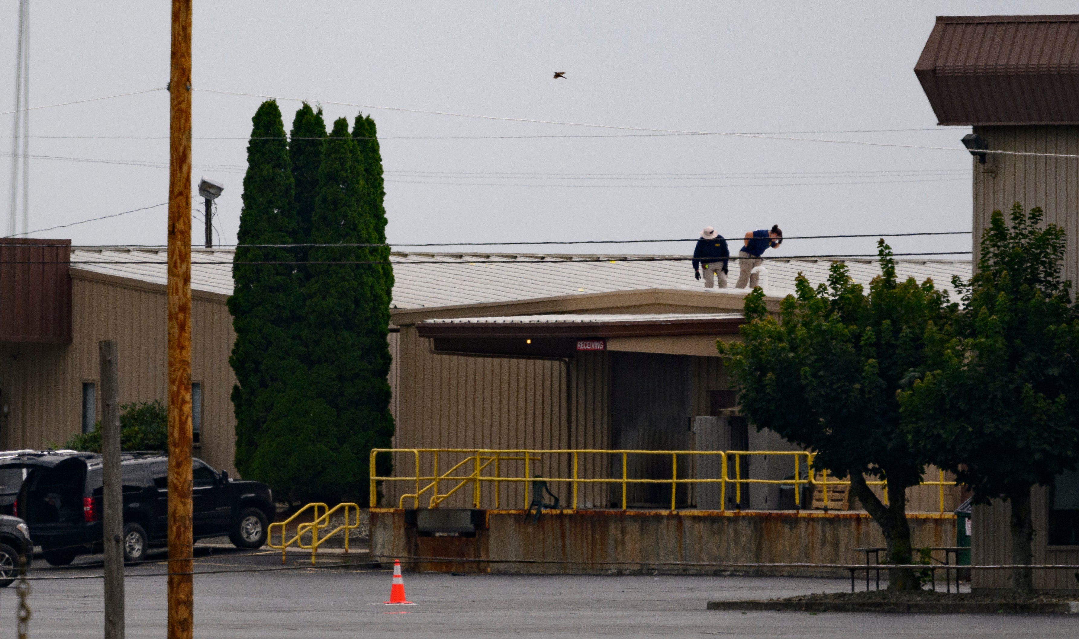 Two FBI investigators scan the roof of AGR International Inc, the building adjacent to the Butler Fairgrounds, from where shooter Matthew Thomas Crooks fired at Trump. Local SWAT has now detailed a lack of communication with Secret Service agents.