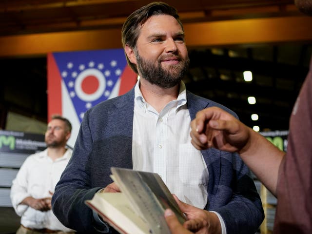 <p>Vance holds a copy of his book ‘Hillbilly Elegy’ as he meets voters in his hometown after announcing his 2022 Senate run</p>