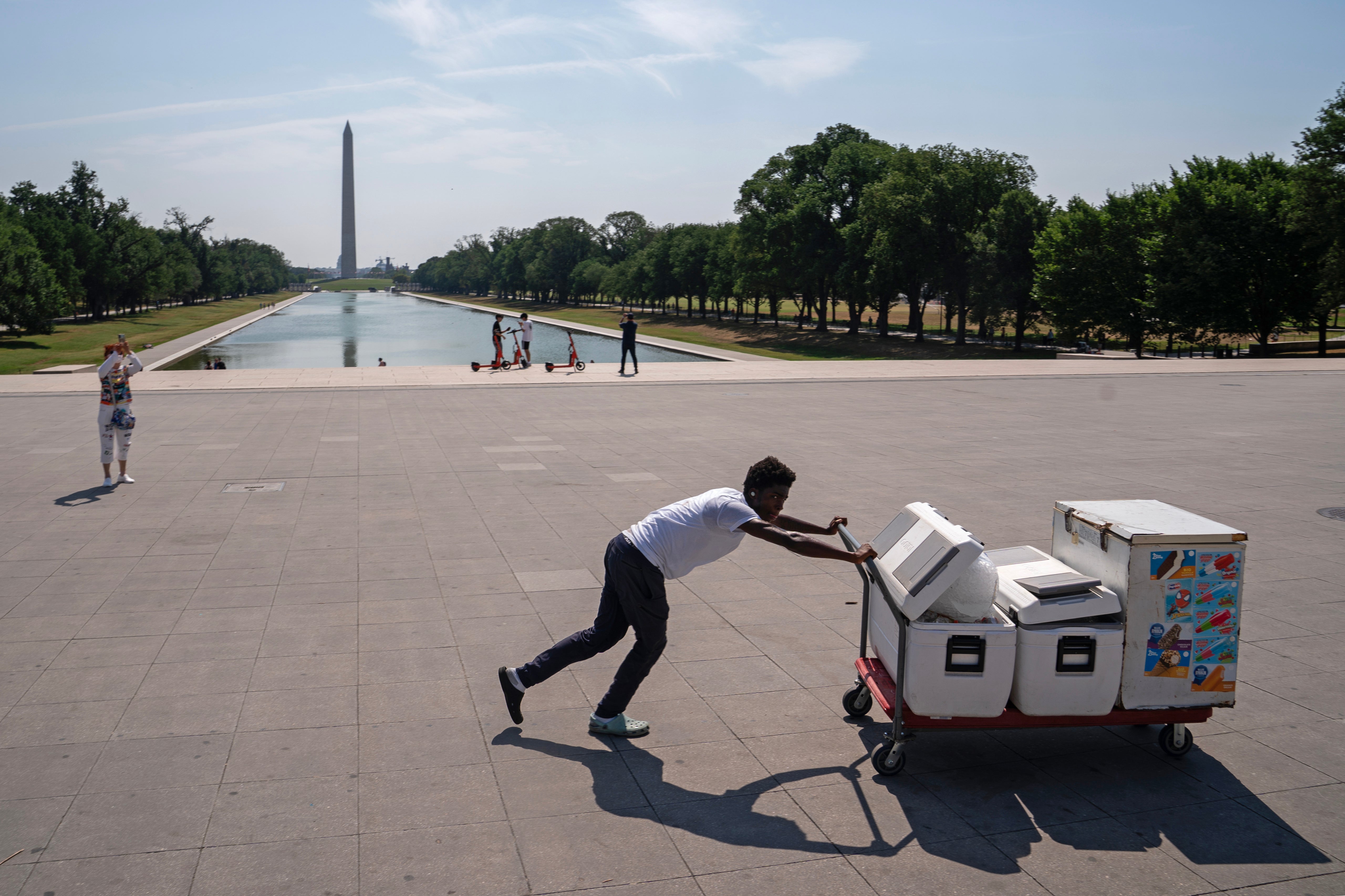 Kendall Brown pushes coolers filled with water to sell near the Lincoln Memorial during a heat wave on July 15, 2024 in Washington, DC. The Washington D.C. area was under an excessive heat 