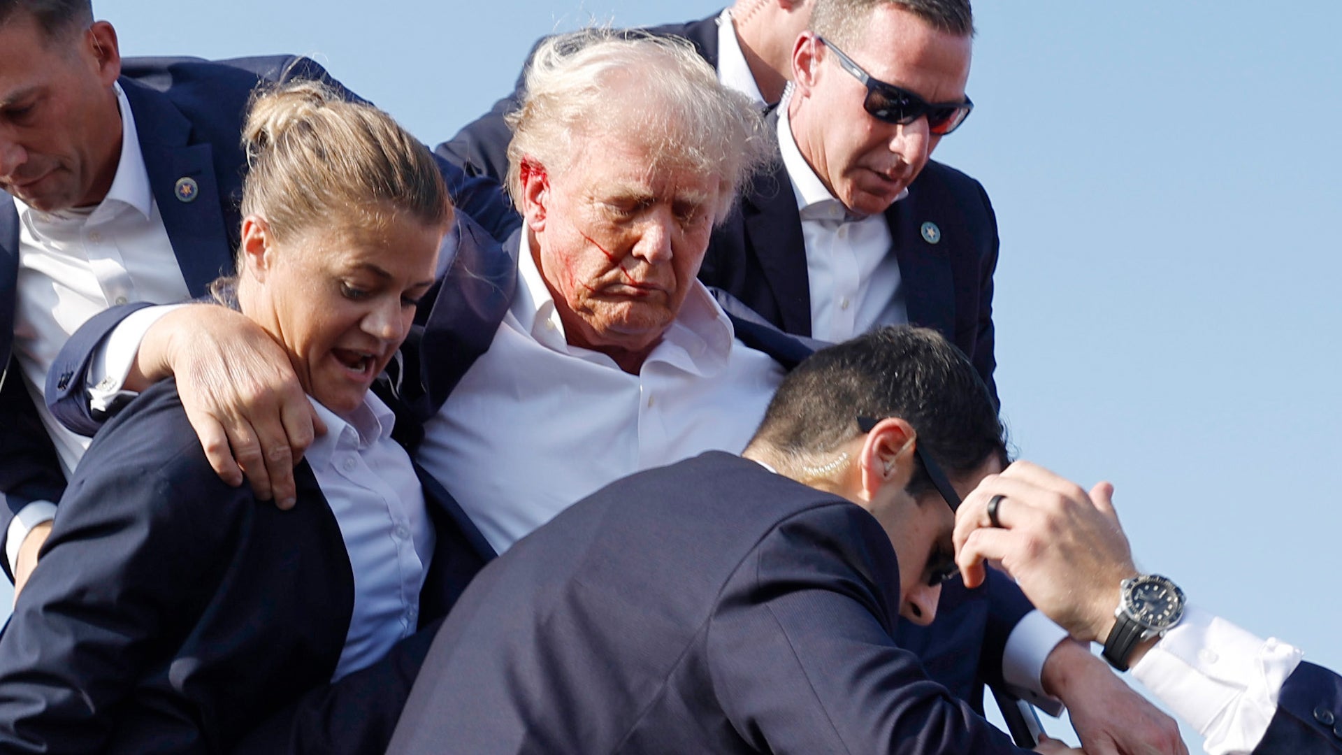 Donald Trump is protected by Secret Service agents in the aftermath of an assassination attempt at a rally in Butler, Pennsylvania