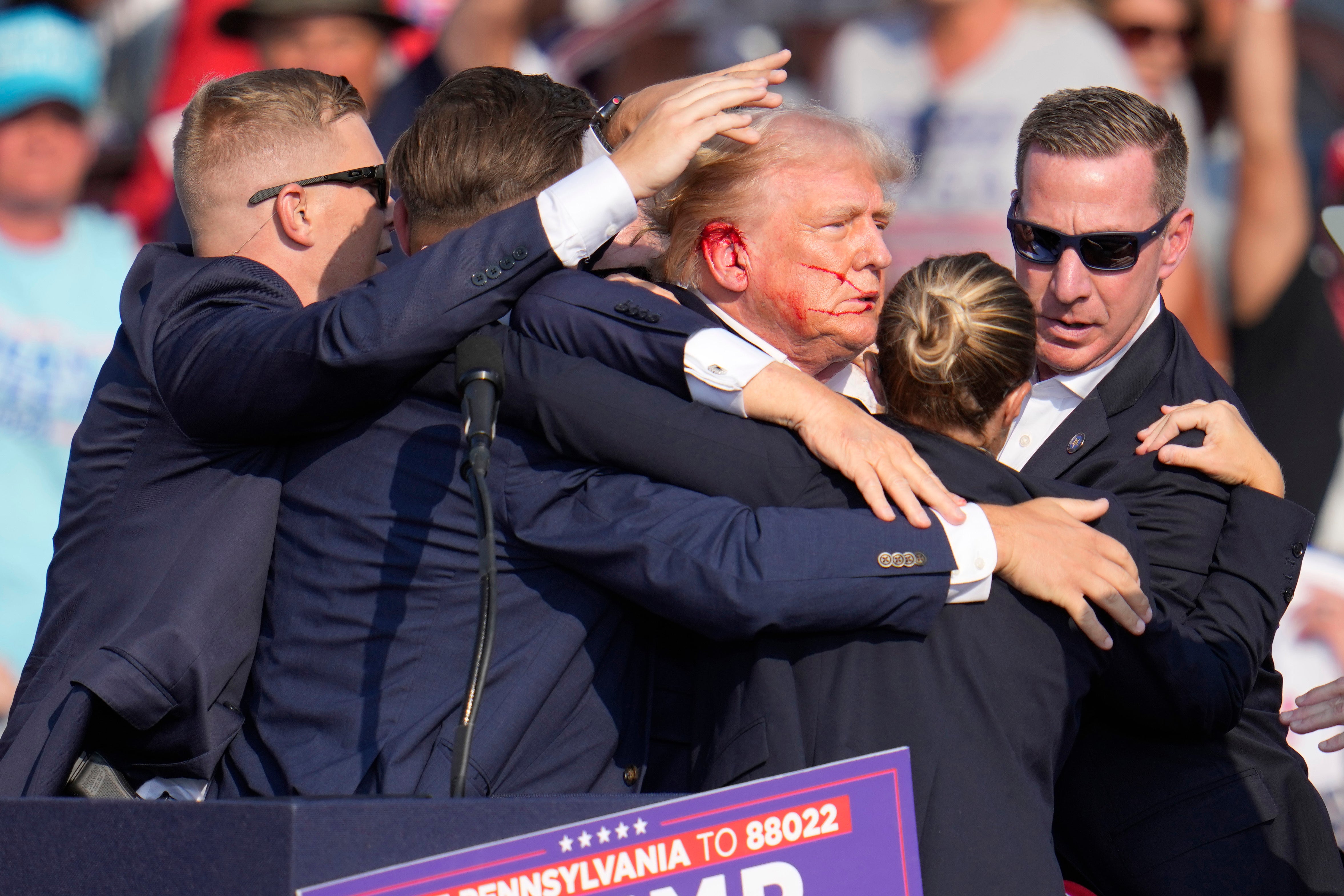 Donald Trump is protected by Secret Service agents in the aftermath of an assassination attempt at a rally in Butler, Pennsylvania