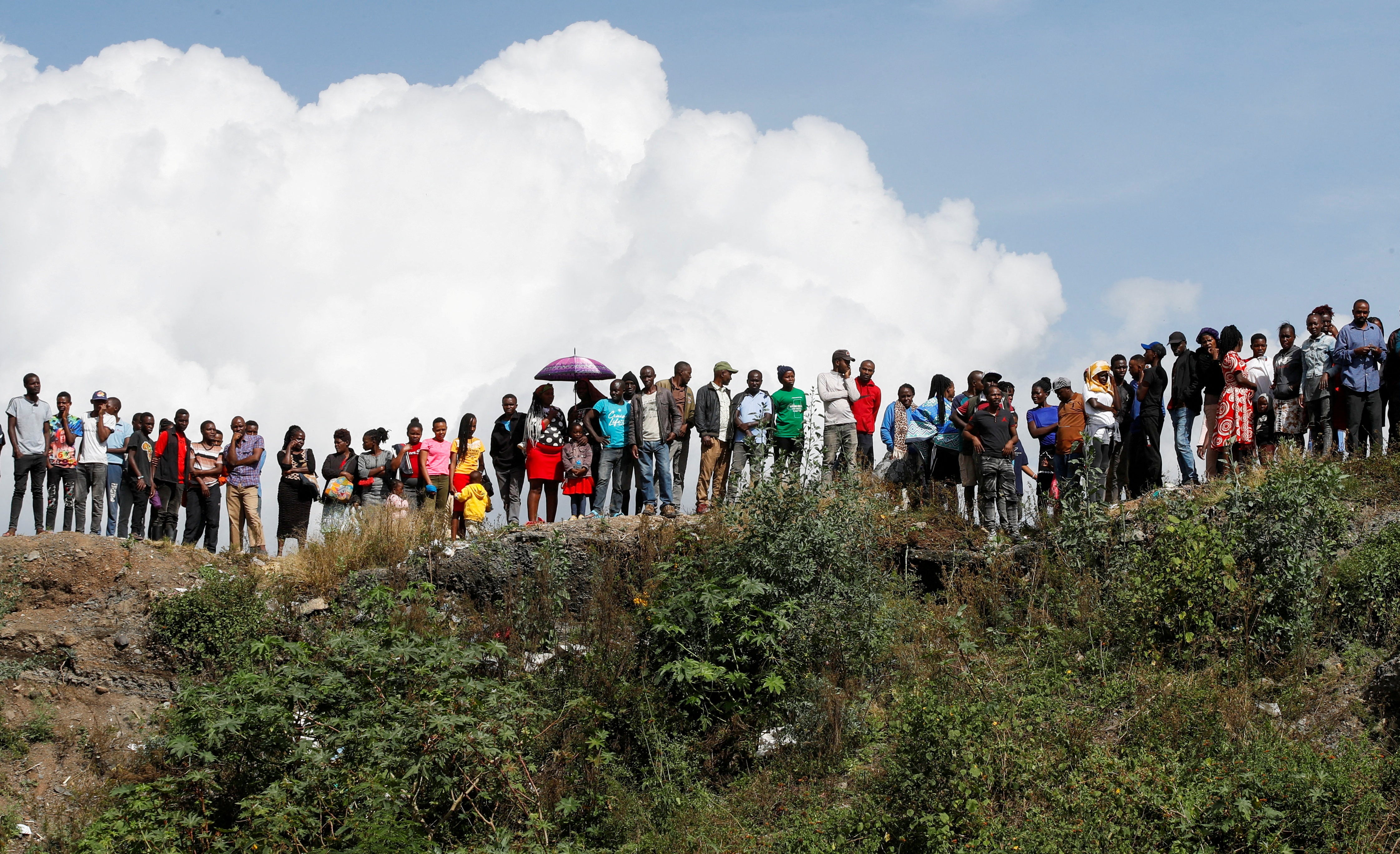 People gather as bodies are retrieved from a dumpsite in the Mukuru slum