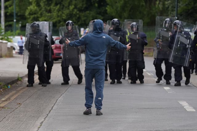 A protester stands in front of a line of gardai during the incident in Coolock, north Dublin (PA)