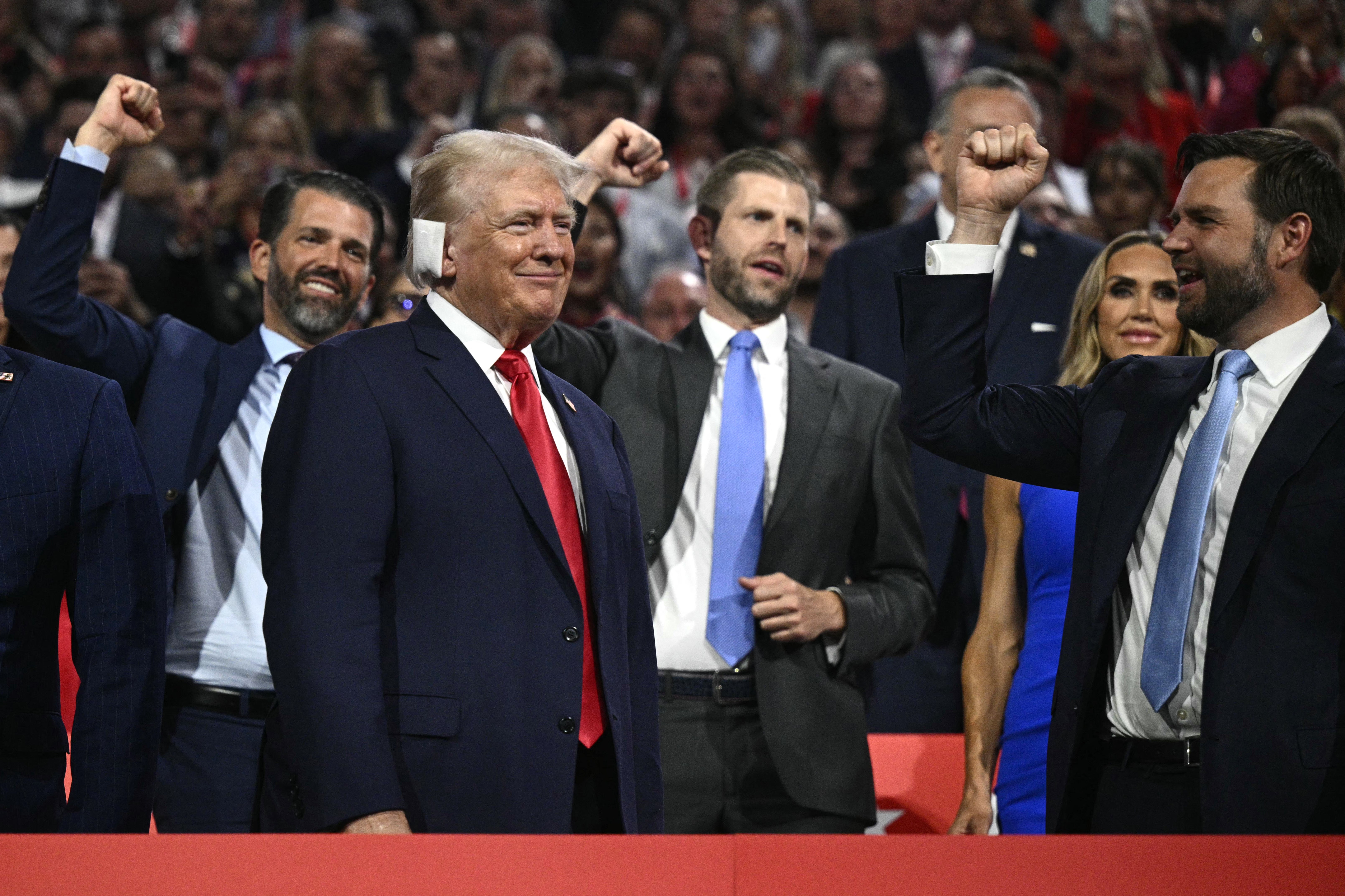 Donald Trump smiles as he is cheered on by JD Vance and his sons Donald Trump Jr and Eric Trump at the RNC