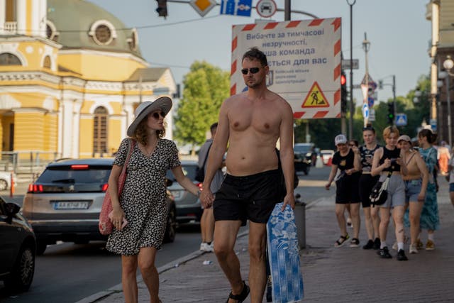 <p>A man and a woman walk down the street on July 14, 2024 in Kyiv, Ukraine. Ukraine has been suffering from extreme heat for the past few weeks</p>
