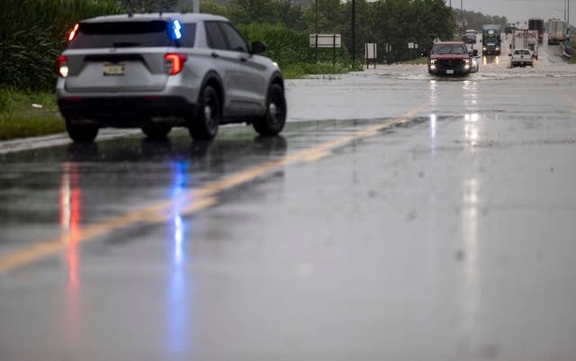 <p>The last set of cars drives through flooding on Illinois State Route 127, south of Interstate 64, before police shut down the road in Nashville, Ill. on Tuesday, July 16, 2024</p>