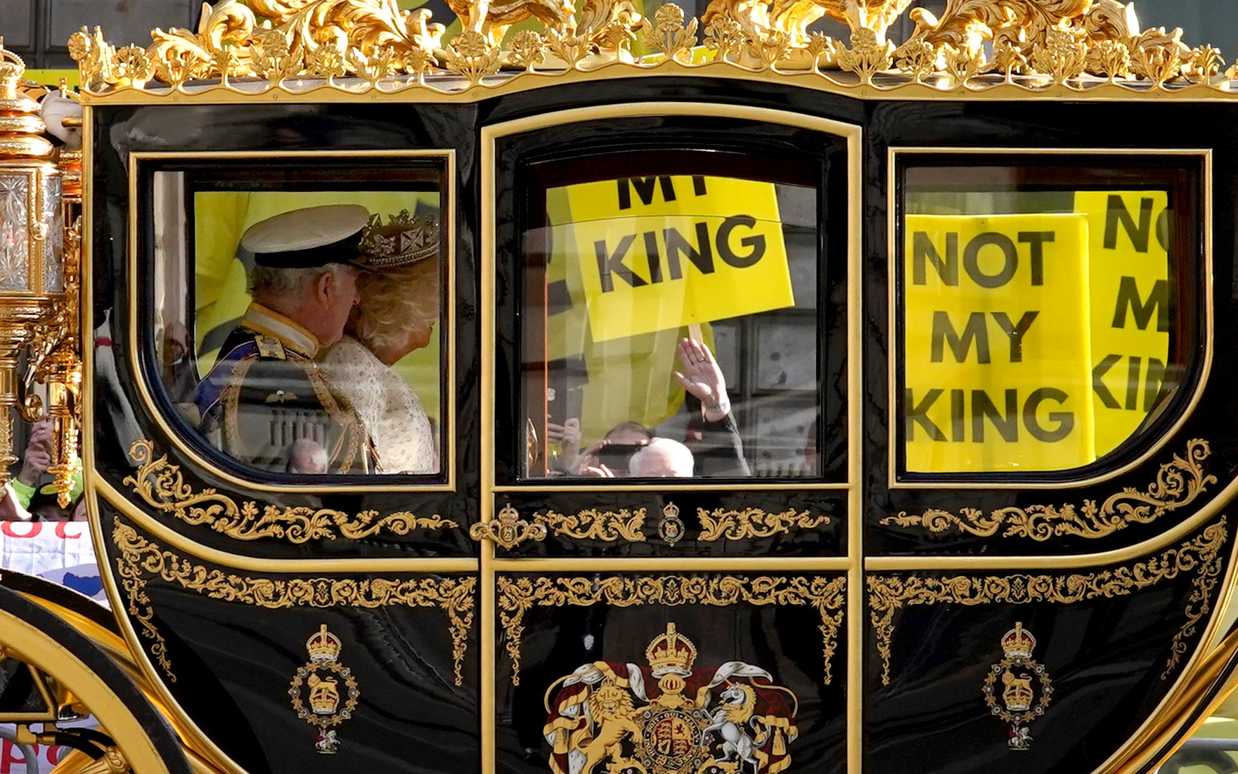 The state coach carrying the King and Queen passes by protesters from anti-monarchy pressure group Republic at the last State Opening of Parliament (Gareth Fuller/PA)