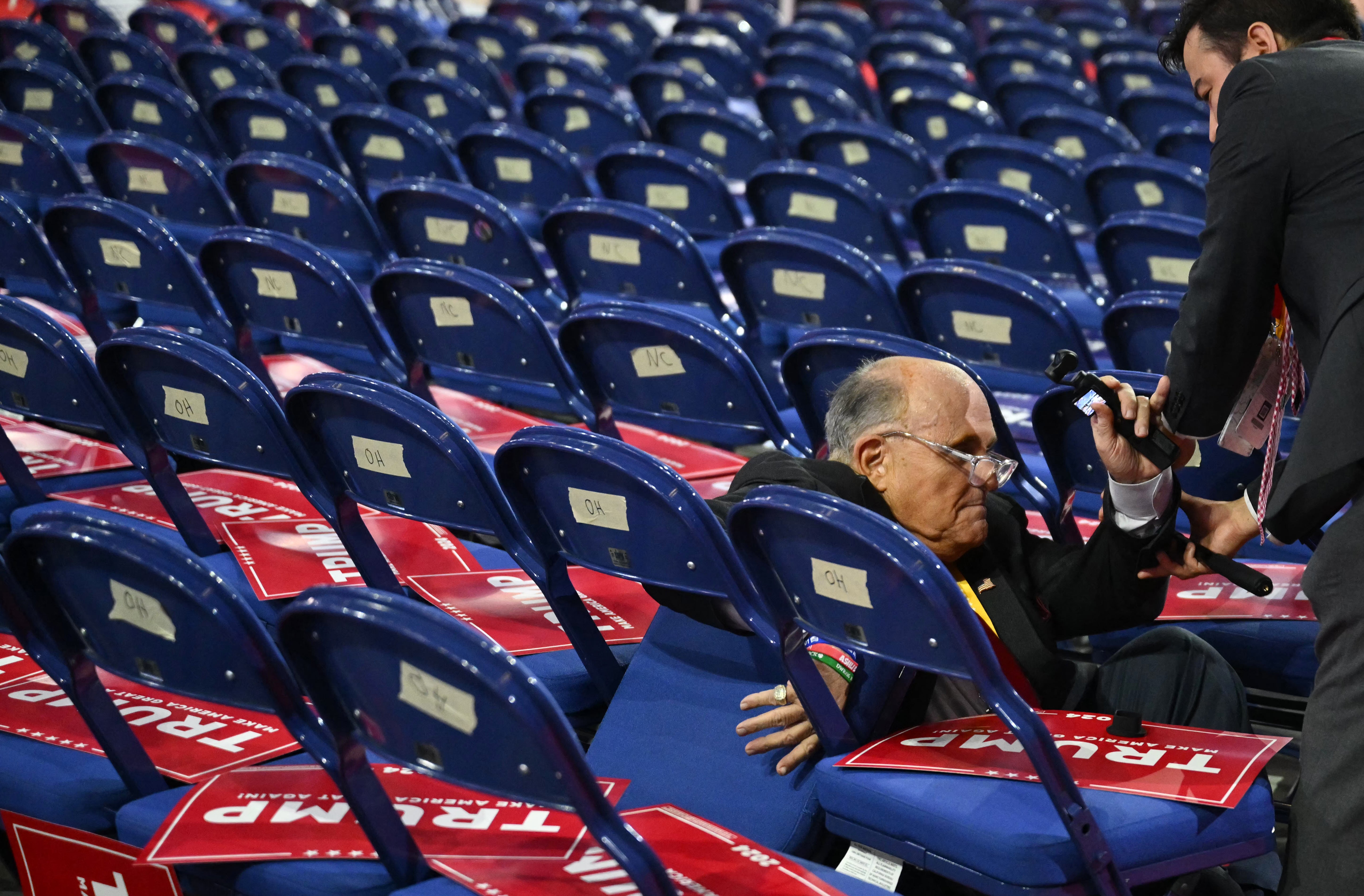 Rudy Giuliani pictured falling onto chairs at the Republican National Convention