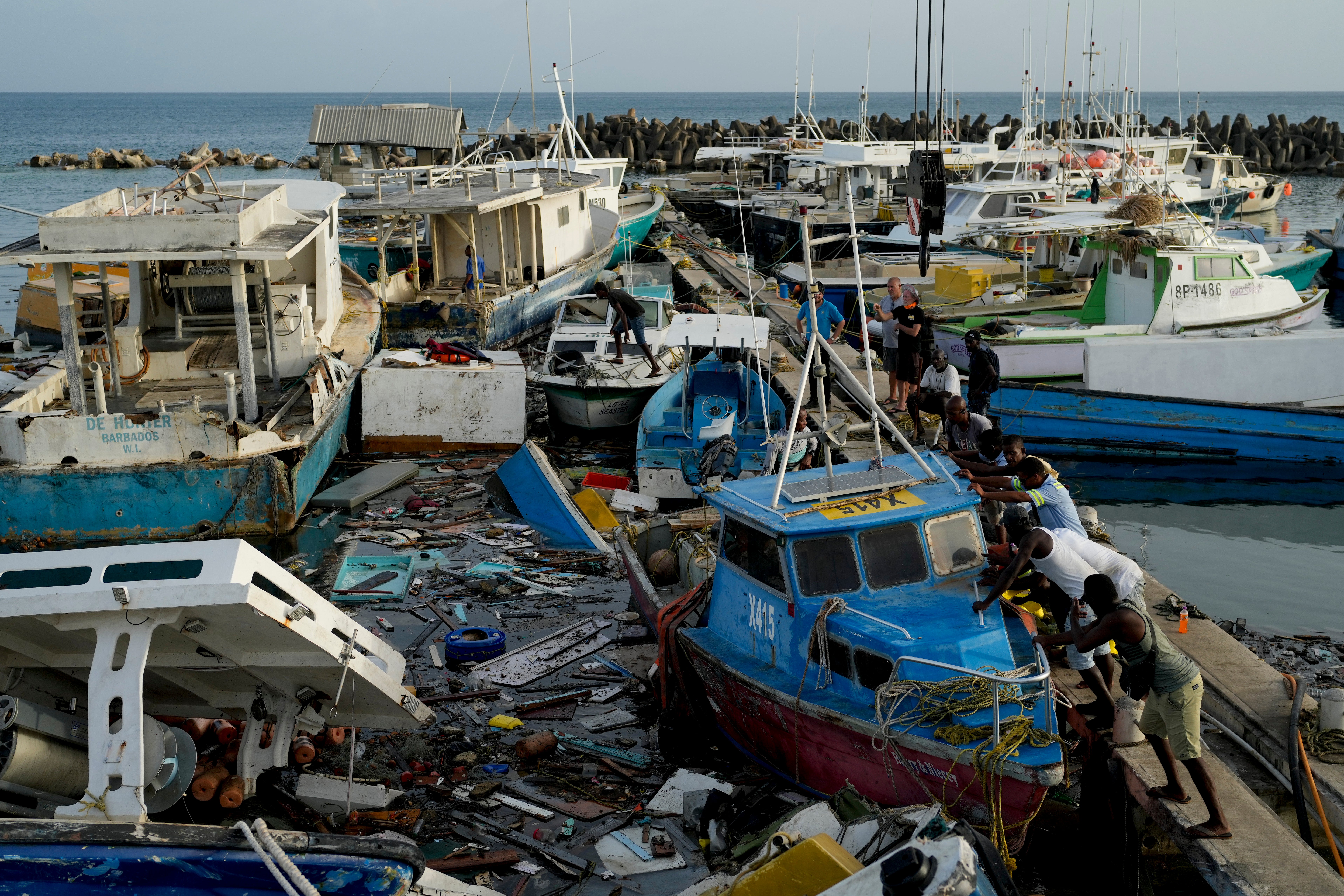 Fishermen push a boat damaged by Hurricane Beryl at the Bridgetown fisheries in Barbados on July 2, 2024
