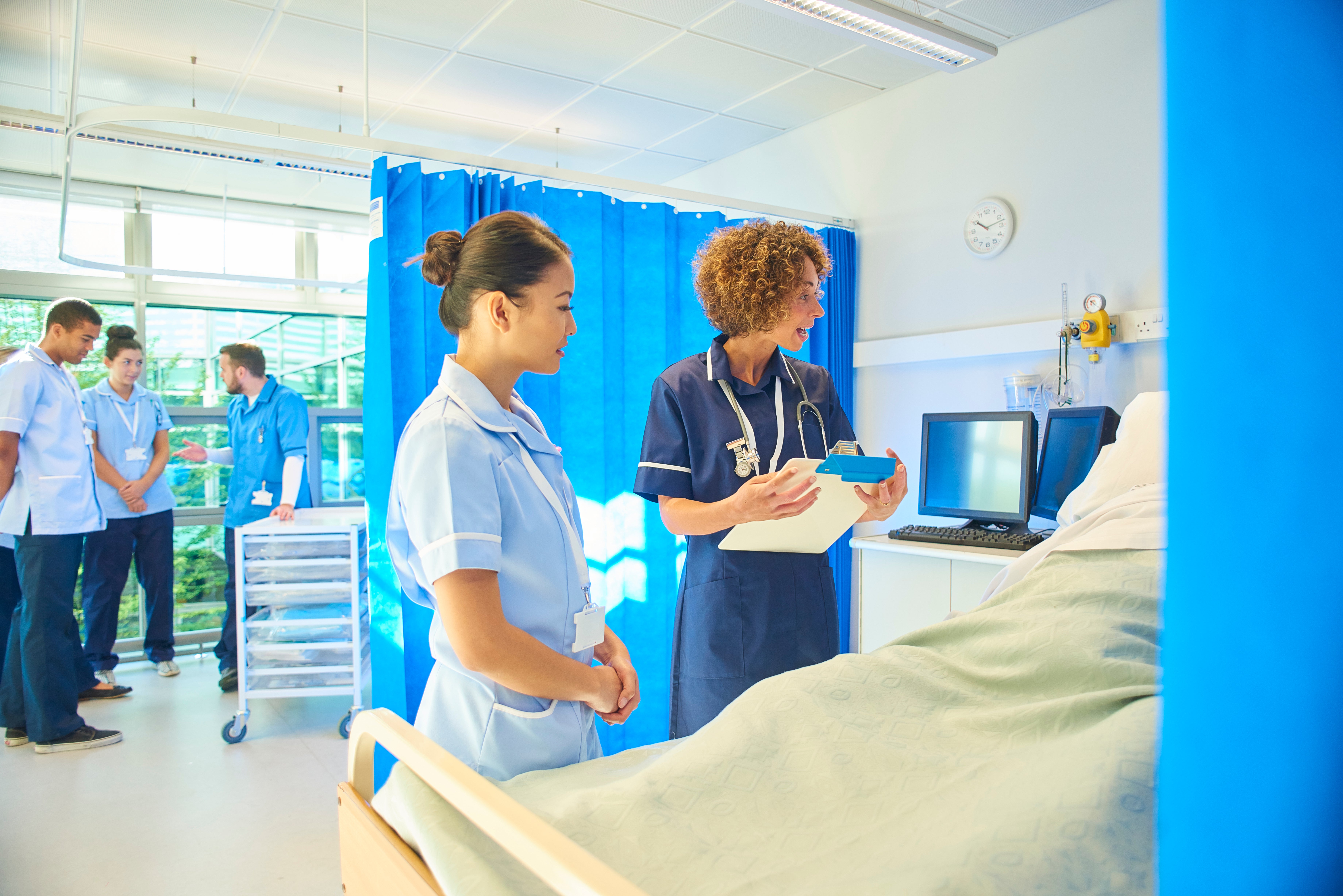 A senior staff nurse instructs a young female nurse