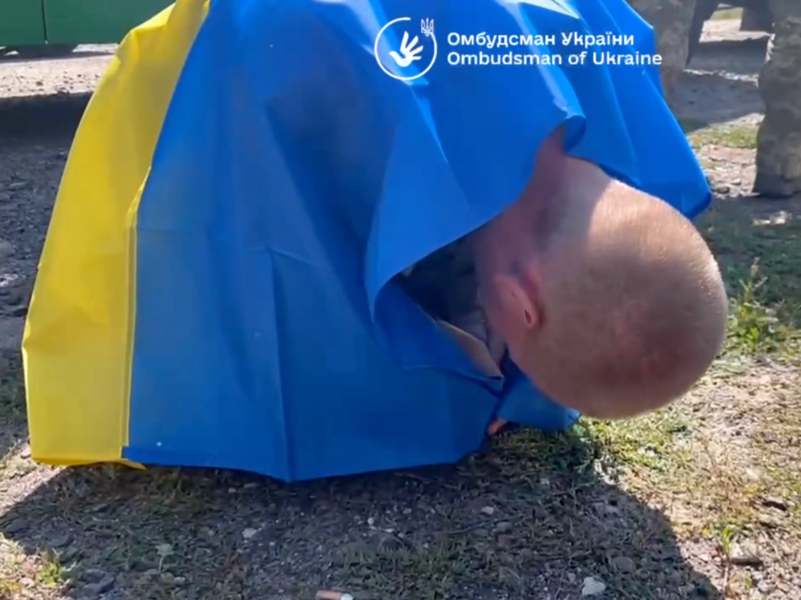 A soldier clutching a Ukrainian flag collapses after returning to his homeland