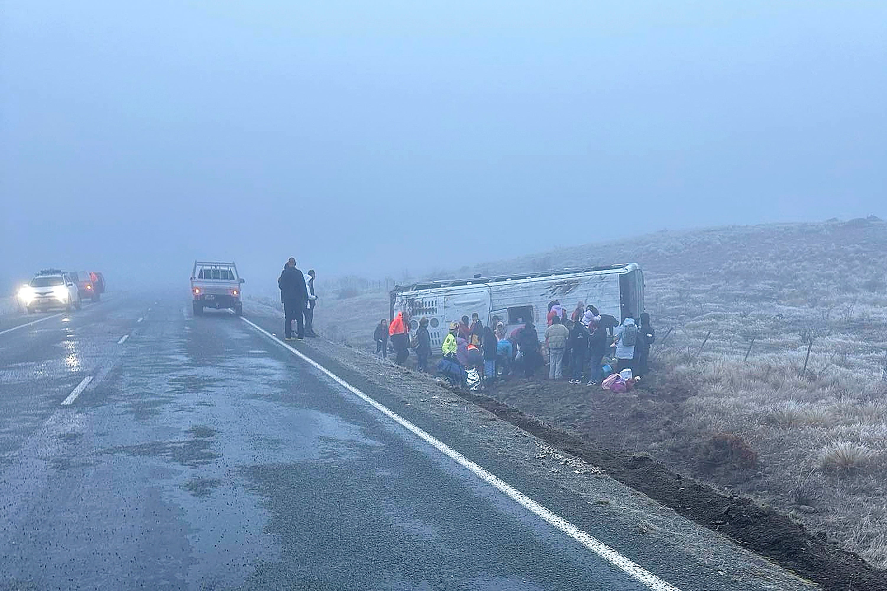 In this photo provided by Grace Duggin, people are in a ditch after a bus carrying Chinese tourists crashed near Lake Tekapo, New Zealand, on Thursday, July 18, 2024. (AP Photo/Grace Duggin)