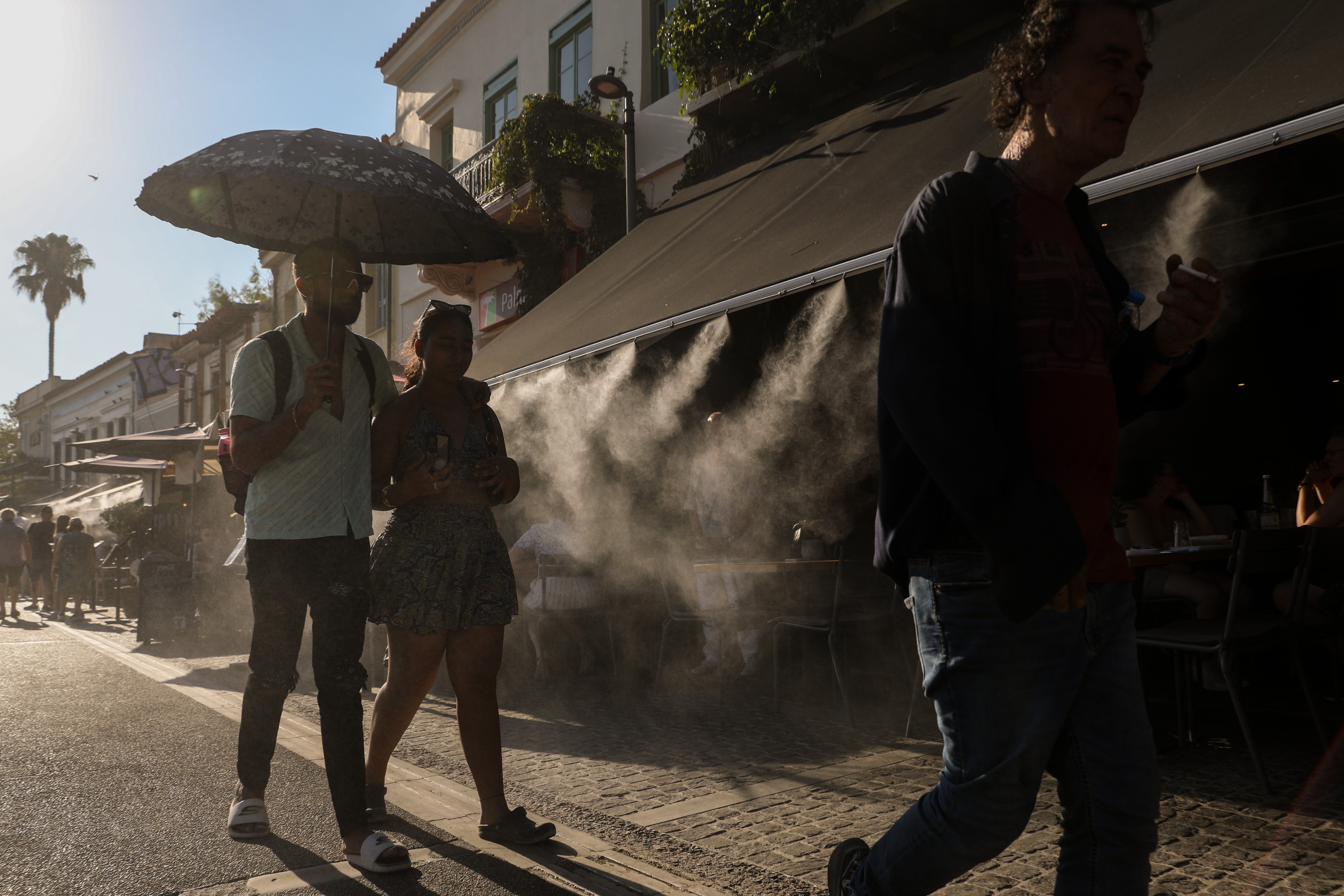Tourists walk past a terrace with a water spray device outside the Ancient Agora during a heatwave in Athens, Greece, 17 July 2024