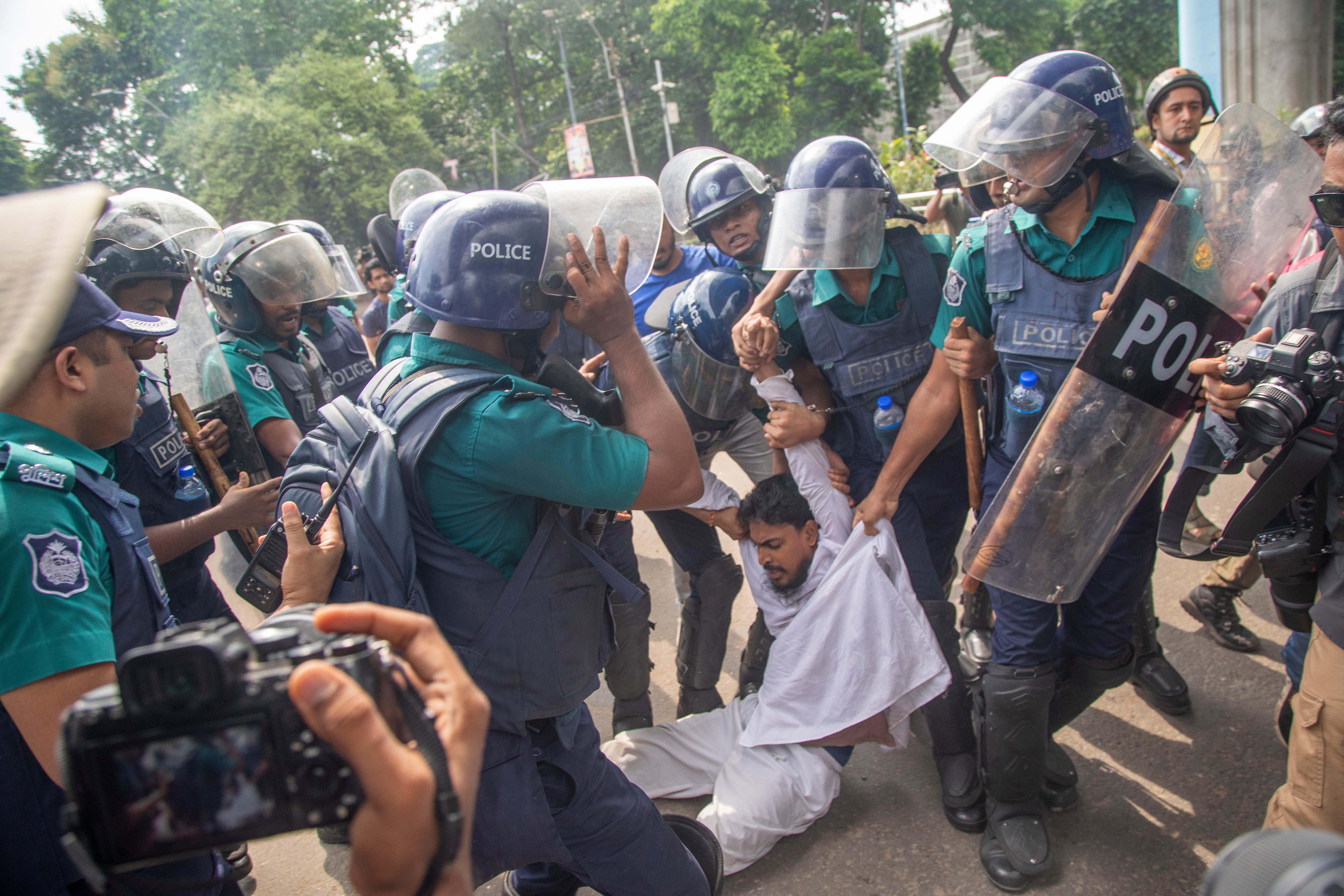 Policemen arrest Akhter Hossain, one of the protesters demanding quota reforms in public service, at Dhaka University campus