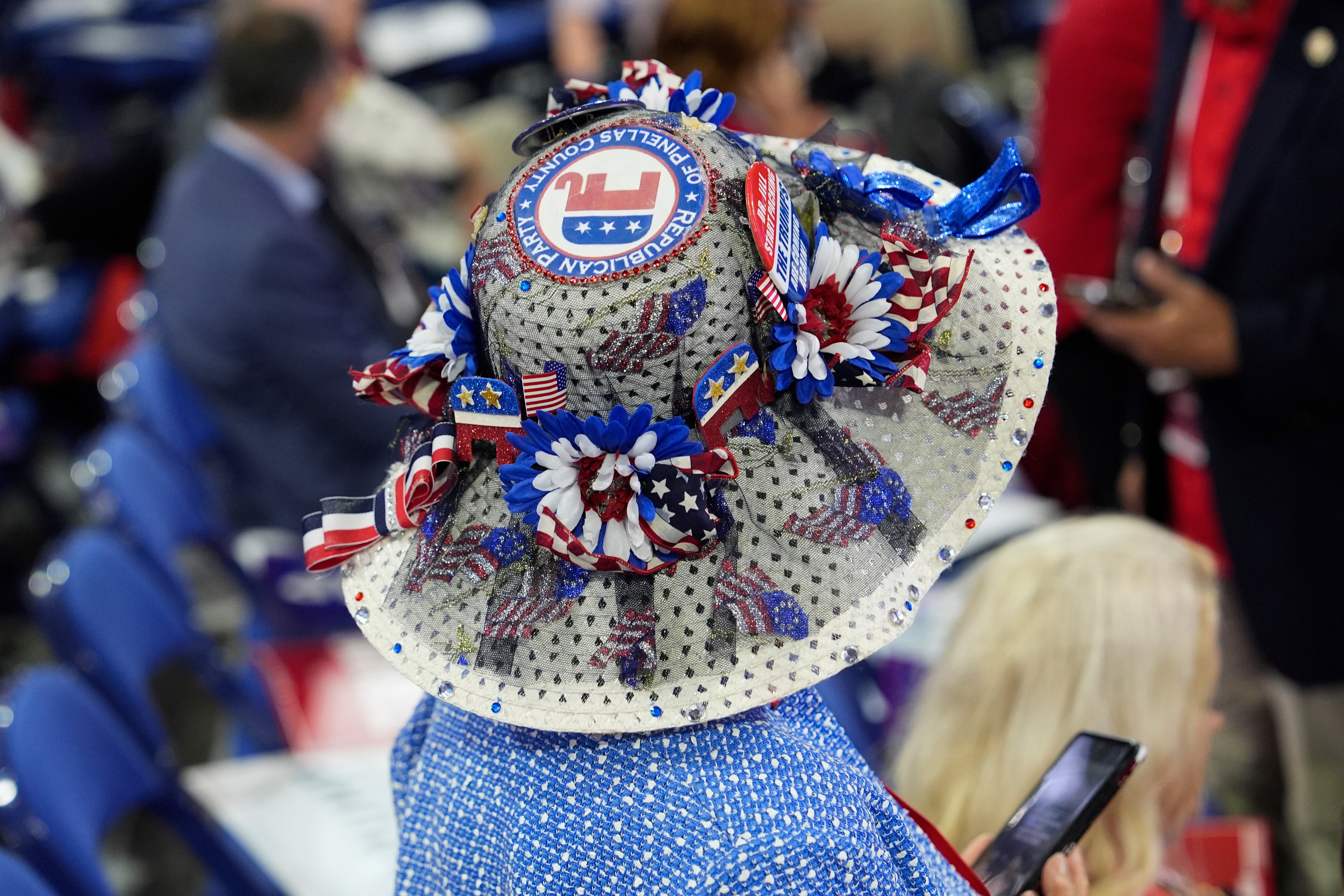 A delegate arrives at the Republican National Convention wearing a gray and white hat decorated with red, white and blue flower pins and the GOP elephant