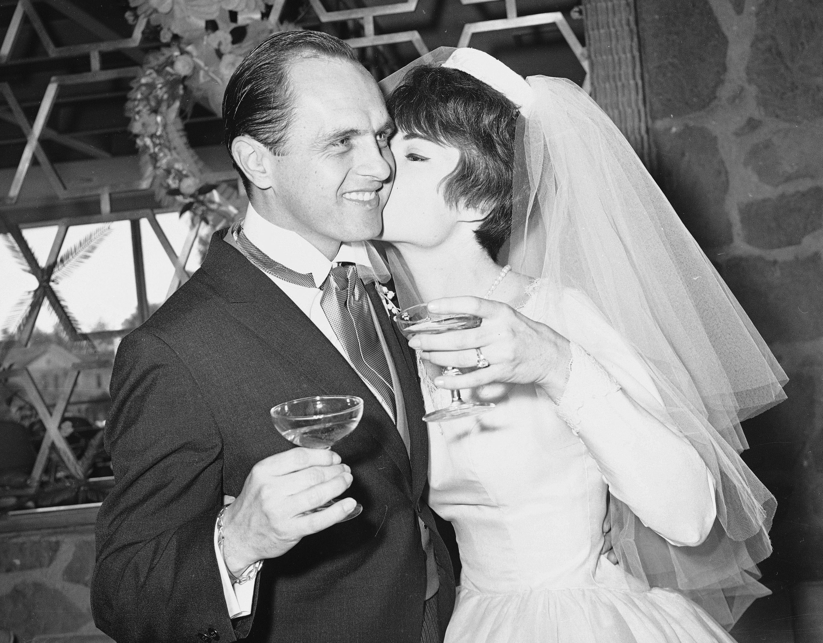 Newhart, 33, and his bride Virginia Quinn, 22, kiss during a toast at the reception that followed their marriage in 1963