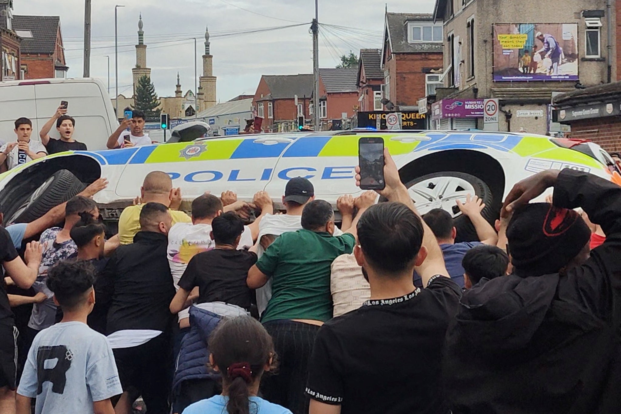 People overturn a police vehicle during the Harehills riots