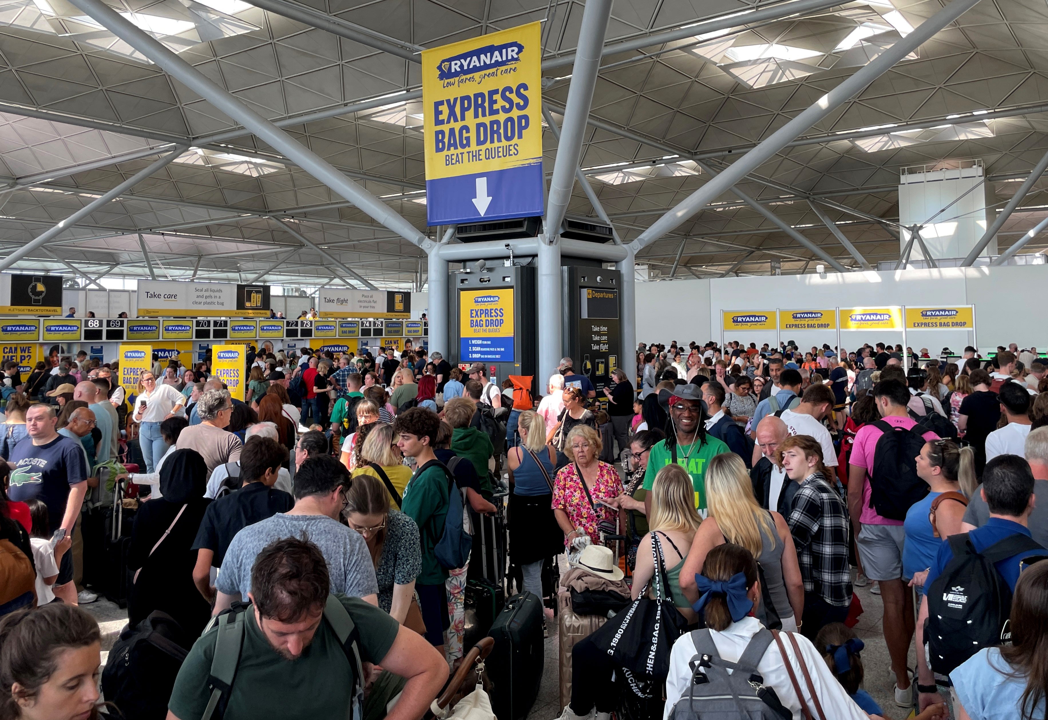 Passengers queue by the Ryanair check-in desk at London Stansted airport