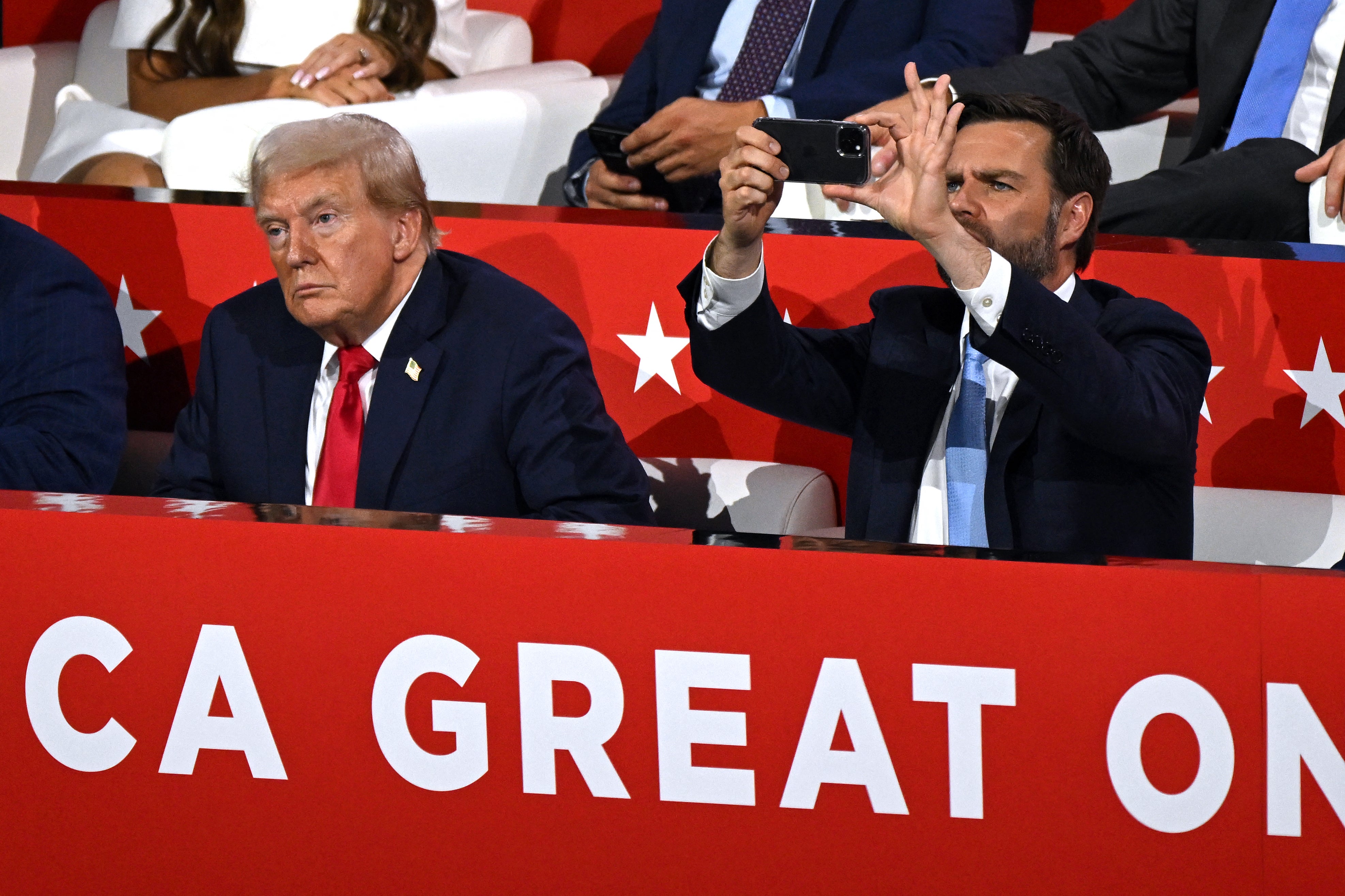 US former President and 2024 Republican presidential candidate Donald Trump (L) looks on as US Senator from Ohio and 2024 Republican vice-president candidate J. D. Vance (R) uses his mobile phone during the first day of the 2024 Republican National Convention at the Fiserv Forum in Milwaukee, Wisconsin, July 15, 2024