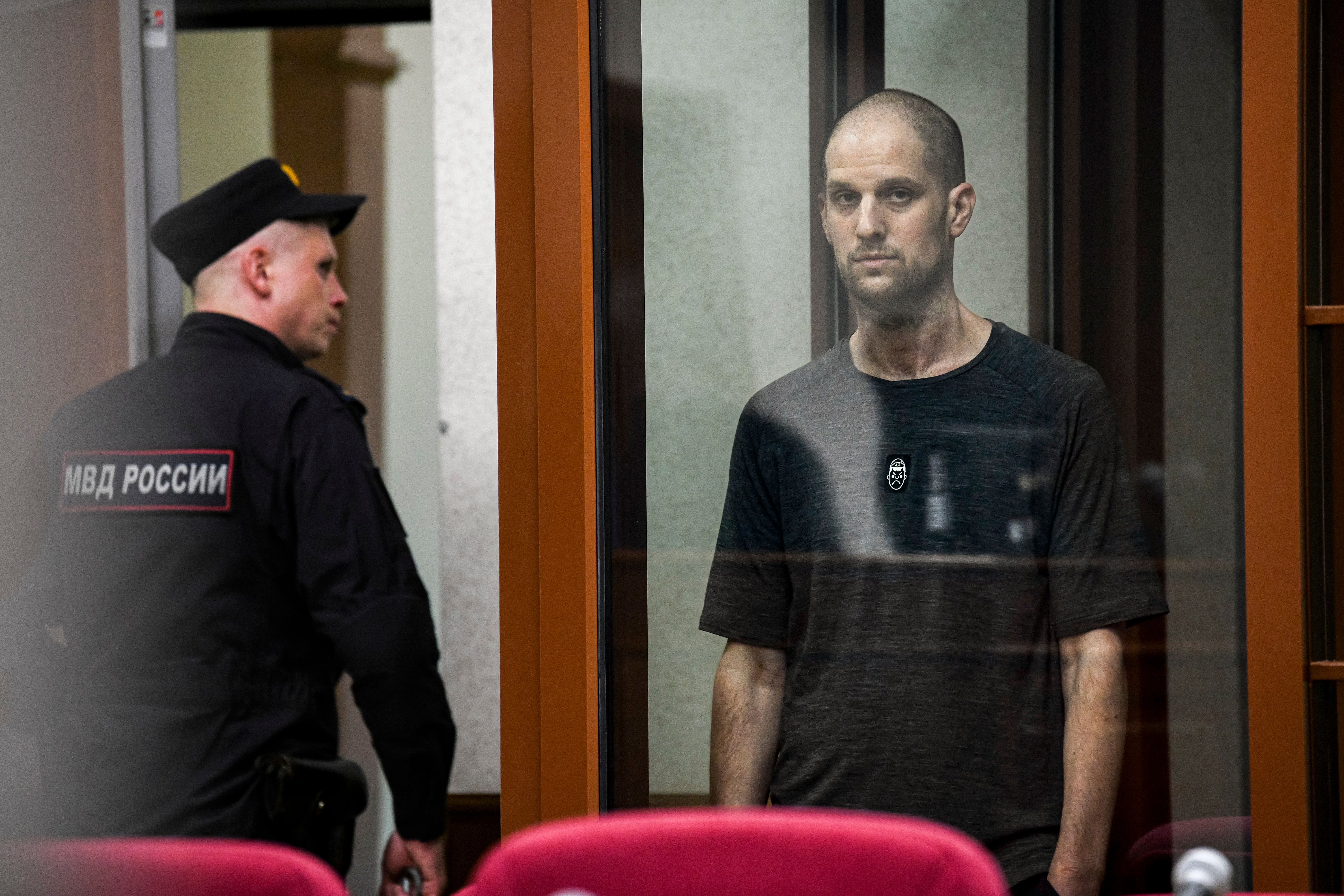 Evan Gershkovich stands listening to the verdict in a glass cage. The Kremlin has indicated that they may be interested in a prisoner exchange