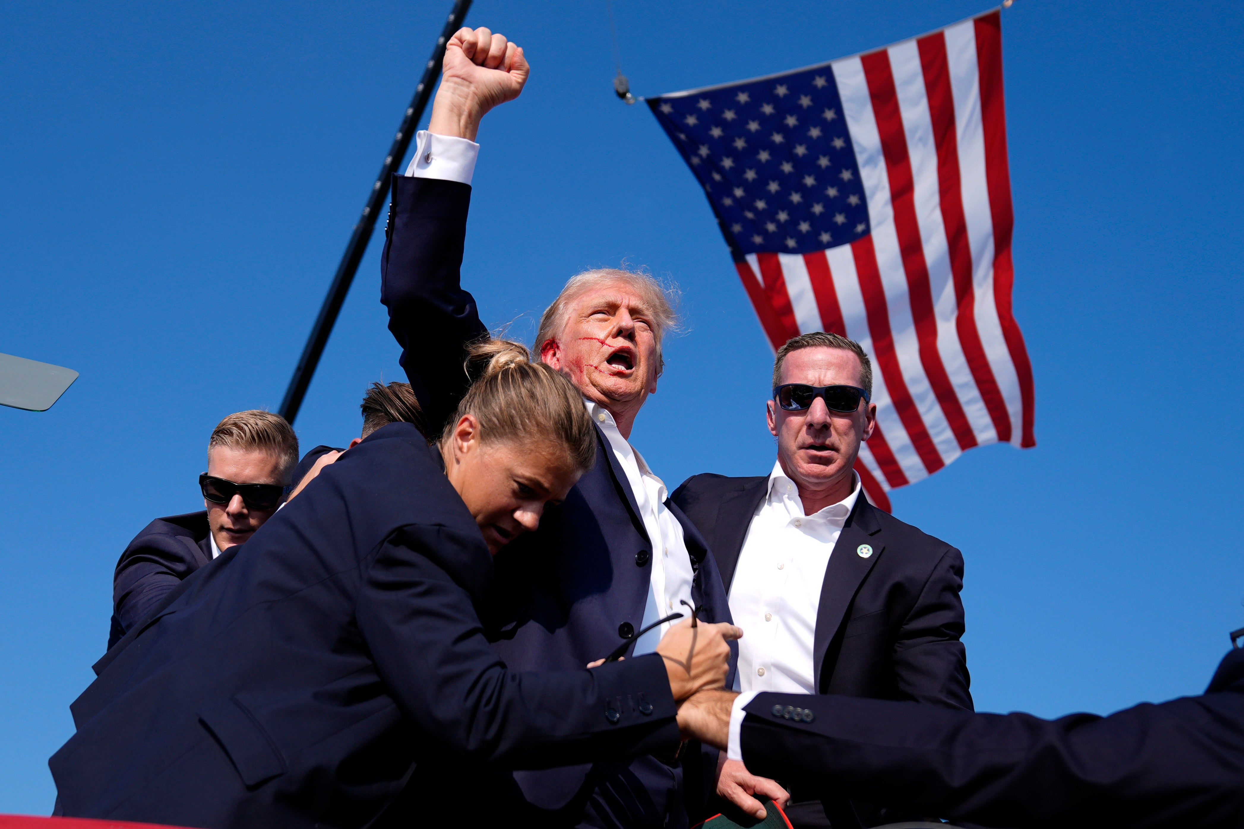 Donald Trump raises a fist as he is rushed from the stage following an assassination attempt at a rally in Pennsylvania earlier this month. He slammed criticism of a female agent as ‘fake news’ following claims that she wasn’t tall enough to protect him