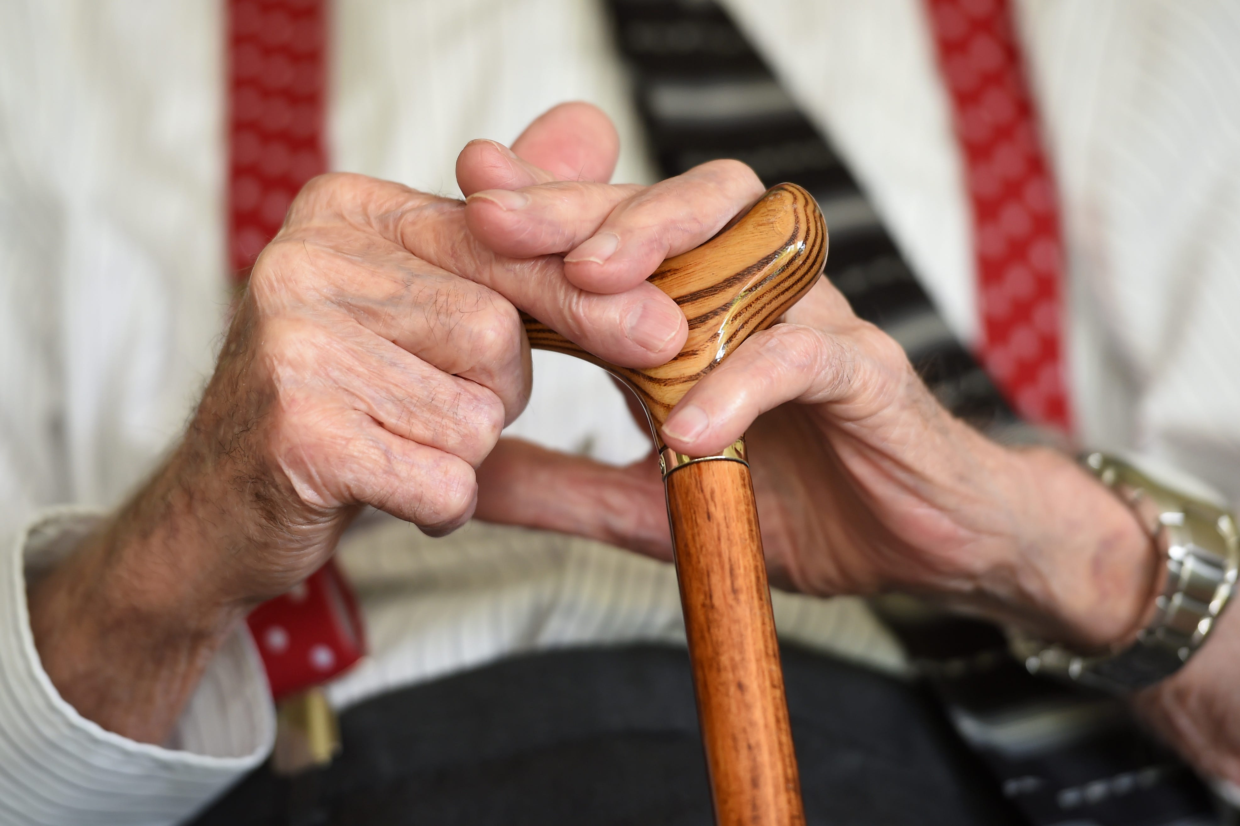 An elderly man holding a walking stick (PA)