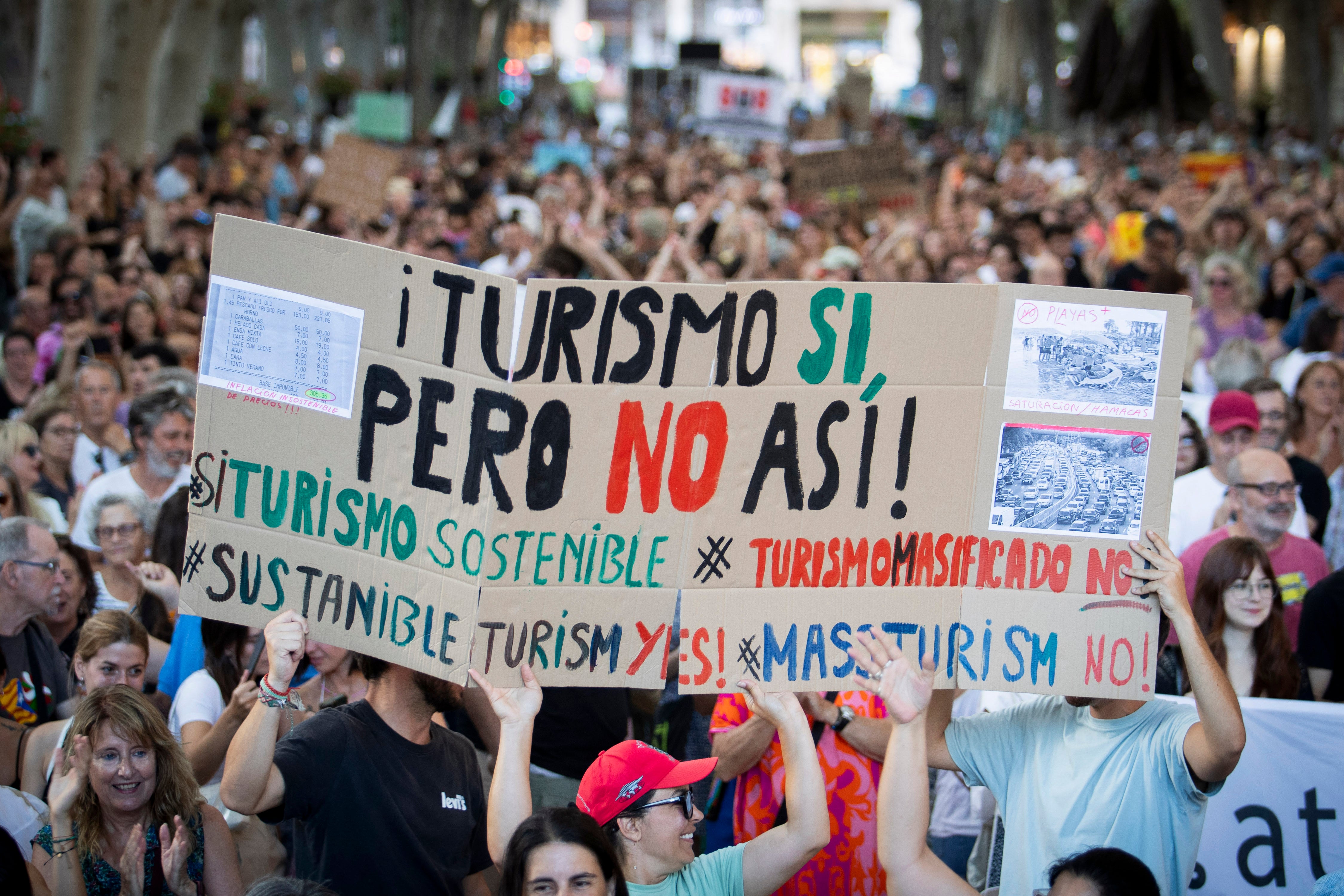 People hold a placard which reads as ‘Tourism yes, but not like this’ during a demonstration to protest against overtourism and housing prices on the island of Mallorca in Palma de Mallorca on July 21, 2024.