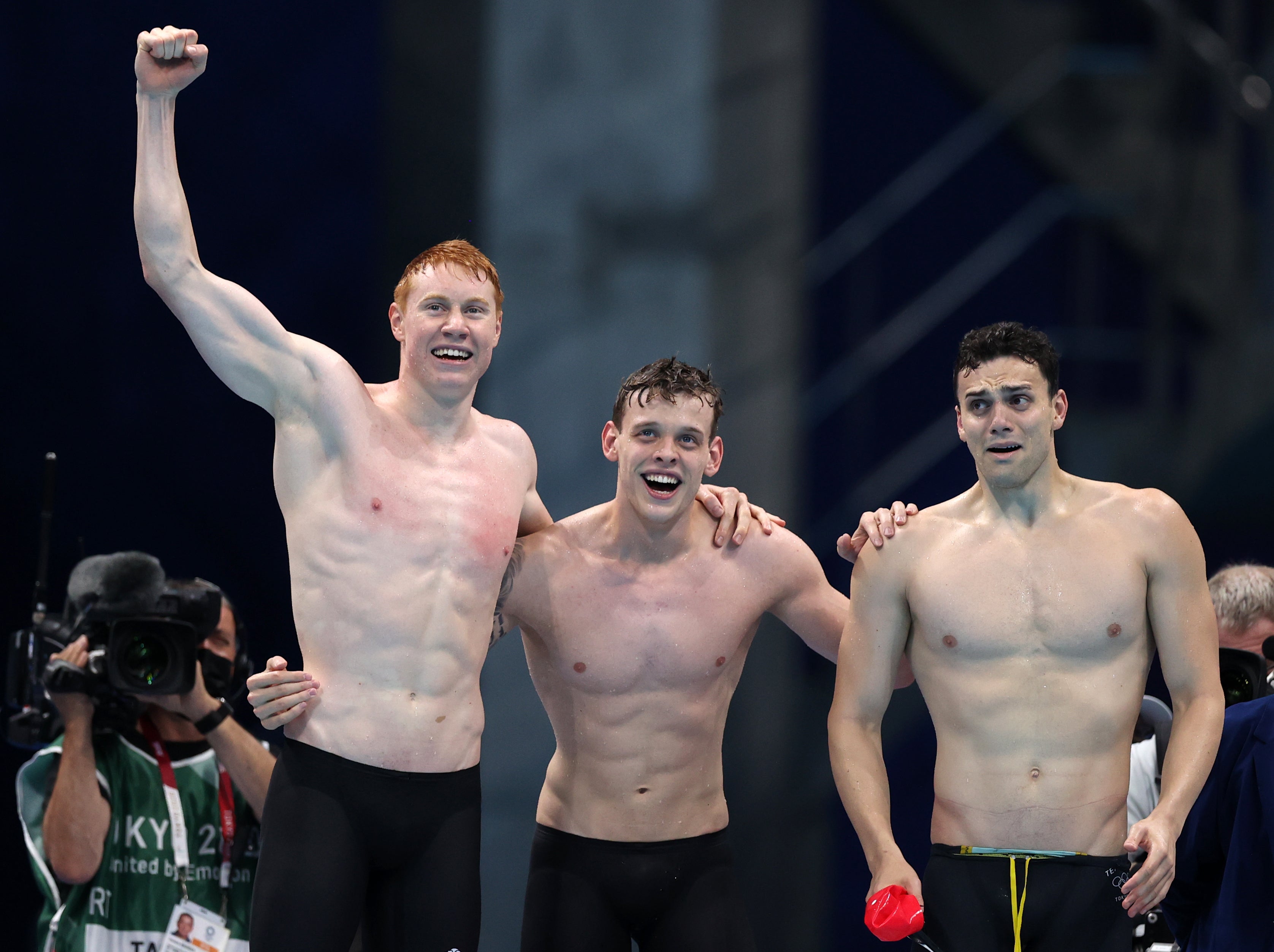 Tom Dean, James Guy and Matthew Richards of Team Great Britain react as teammate Duncan Scott swims the anchor leg in Tokyo