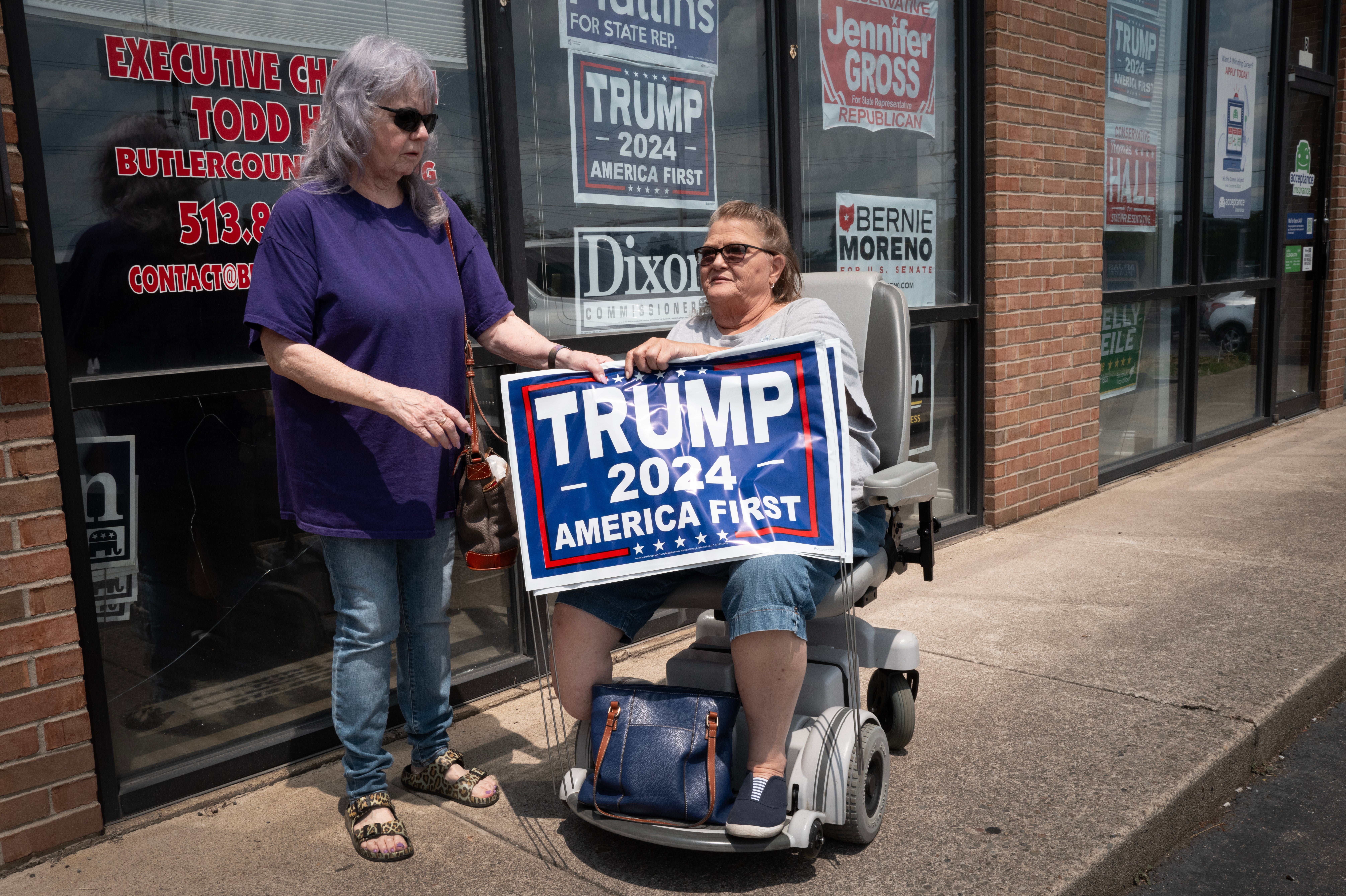 Women leave the headquarters of the Butler County Republican Party carrying campaign yard signs supporting Republican presidential candidate former president Donald Trump on 23 July 2024 in Middletown, Ohio