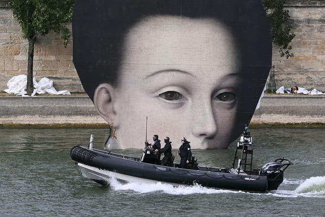<p>Members of police forces patrol on boat along Seine river next to a pannel depicting a pictorial detail ahead of the opening ceremony of the Paris 2024 Olympic Games</p>