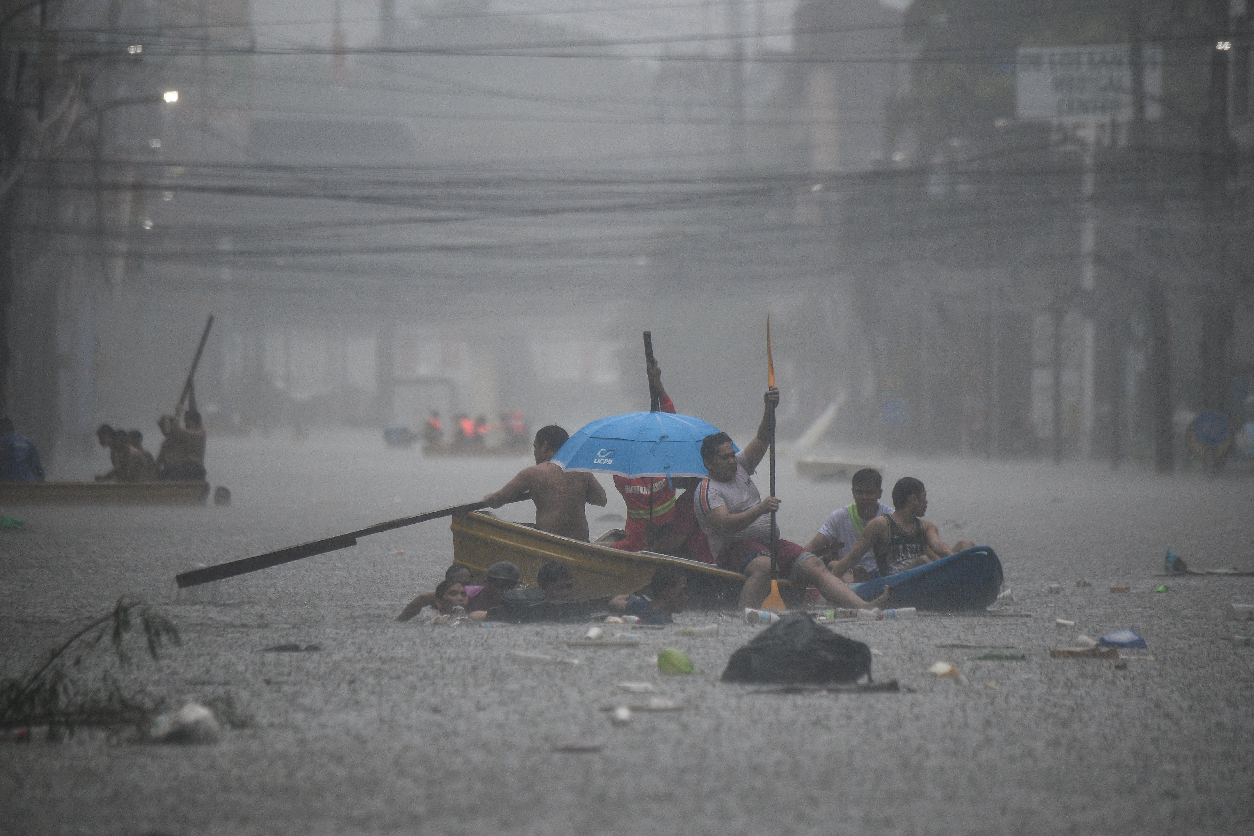 Rescuers paddle their boats along a flooded street in Manila amid heavy rains brought by Typhoon Gaemi