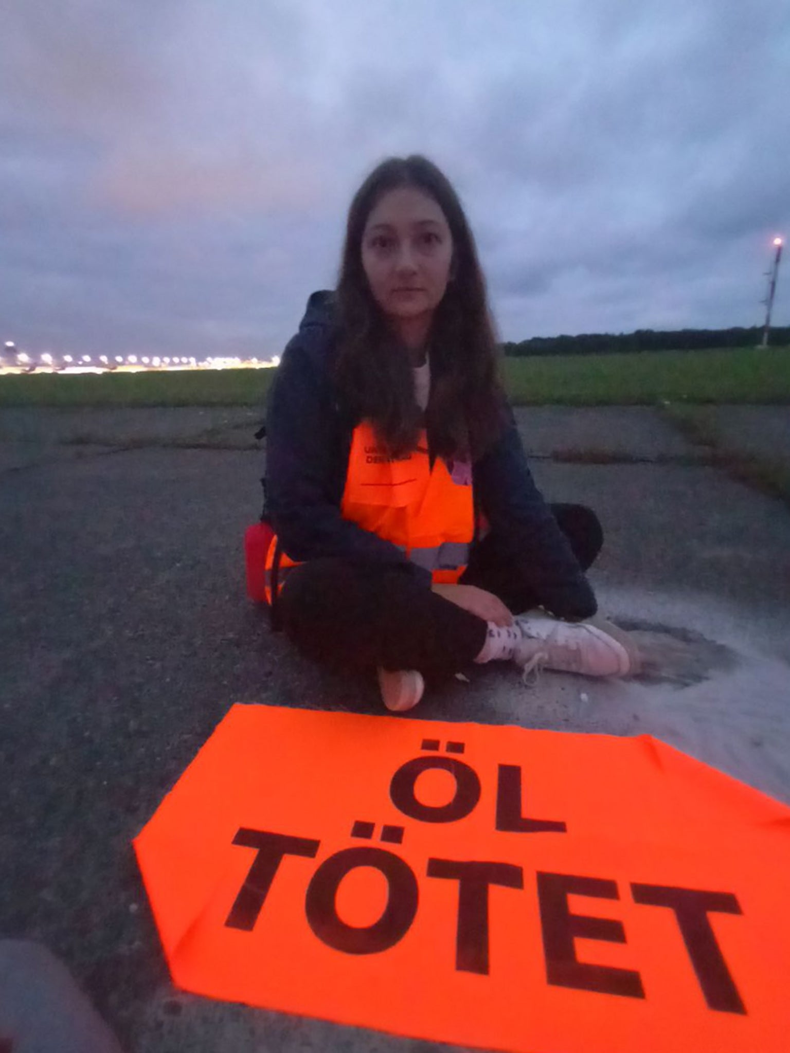 A Last Generation activist with her hands glued to the runway at Cologne-Bonn airport