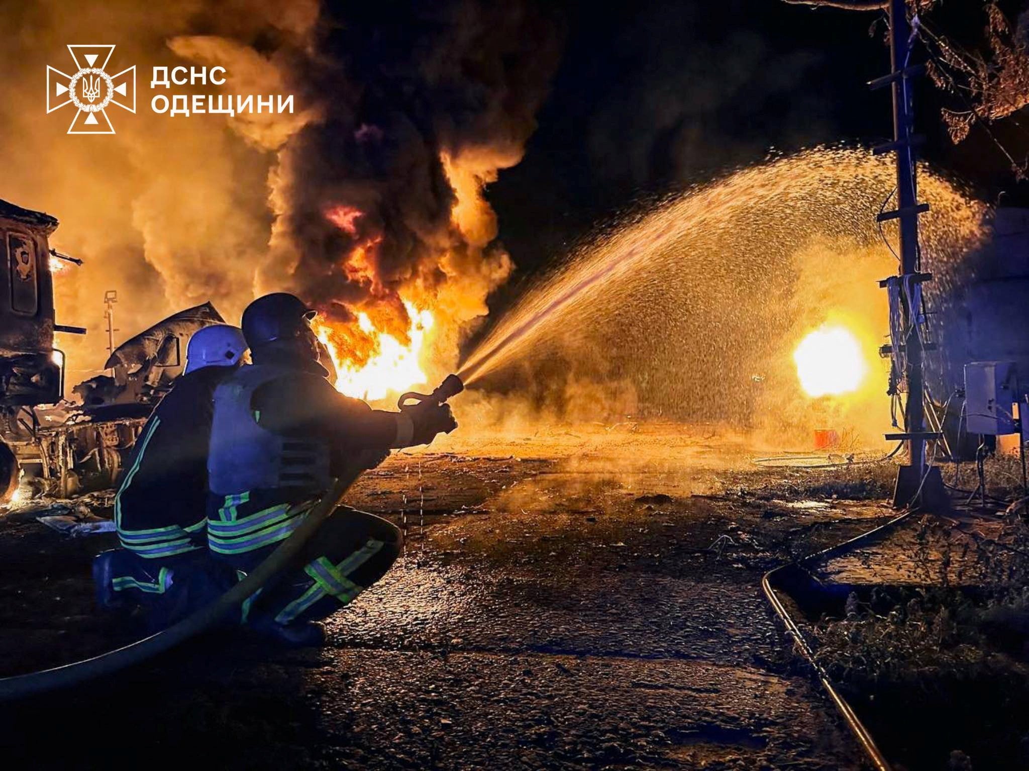 Members of emergency services use a water hose as flames and smoke rise in the aftermath of a Russian drone strike, amid Russia's invasion of Ukraine, in a location given as Izmail