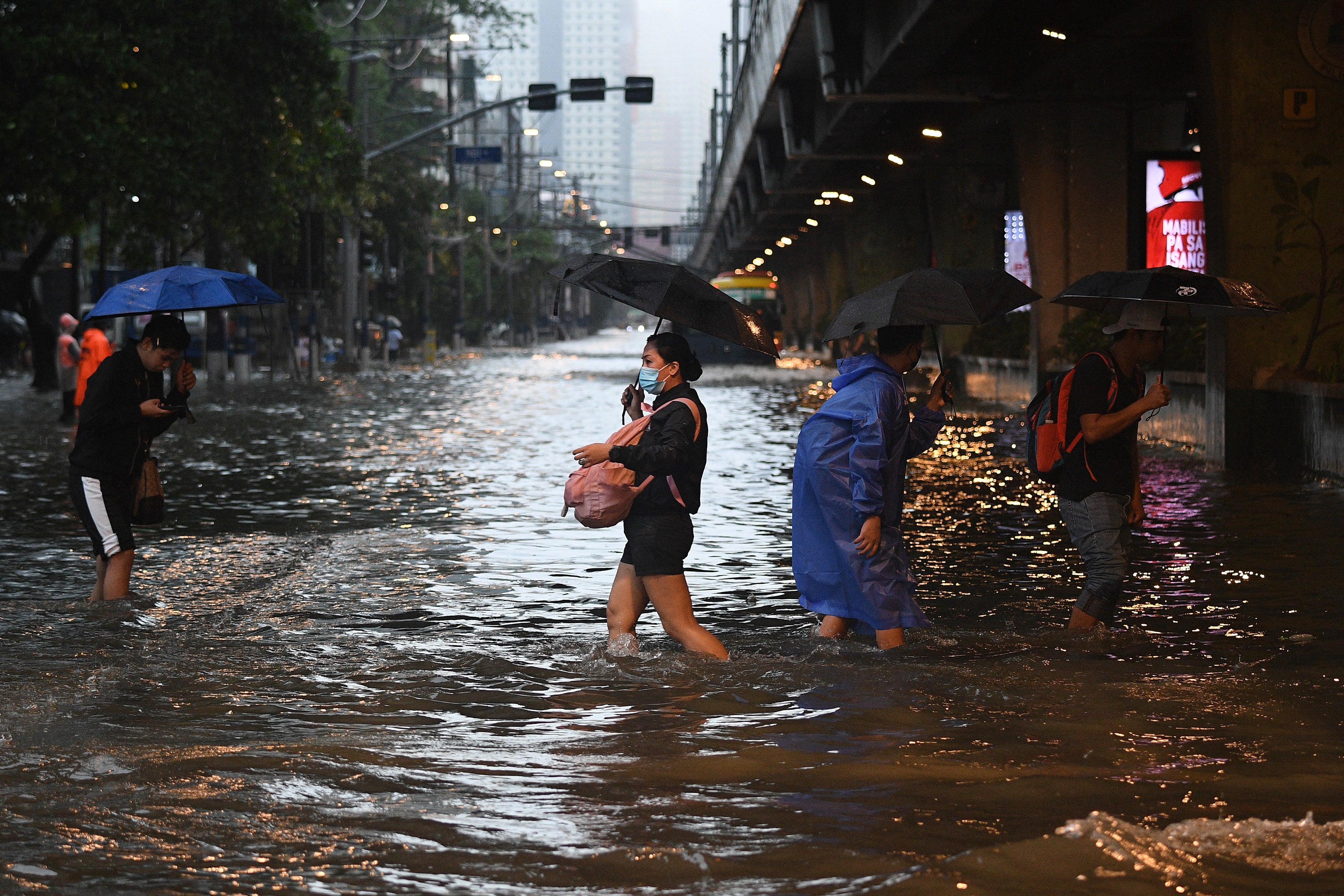 Pedestrians cross a flooded street in Manila during heavy rains from Typhoon Gaemi.