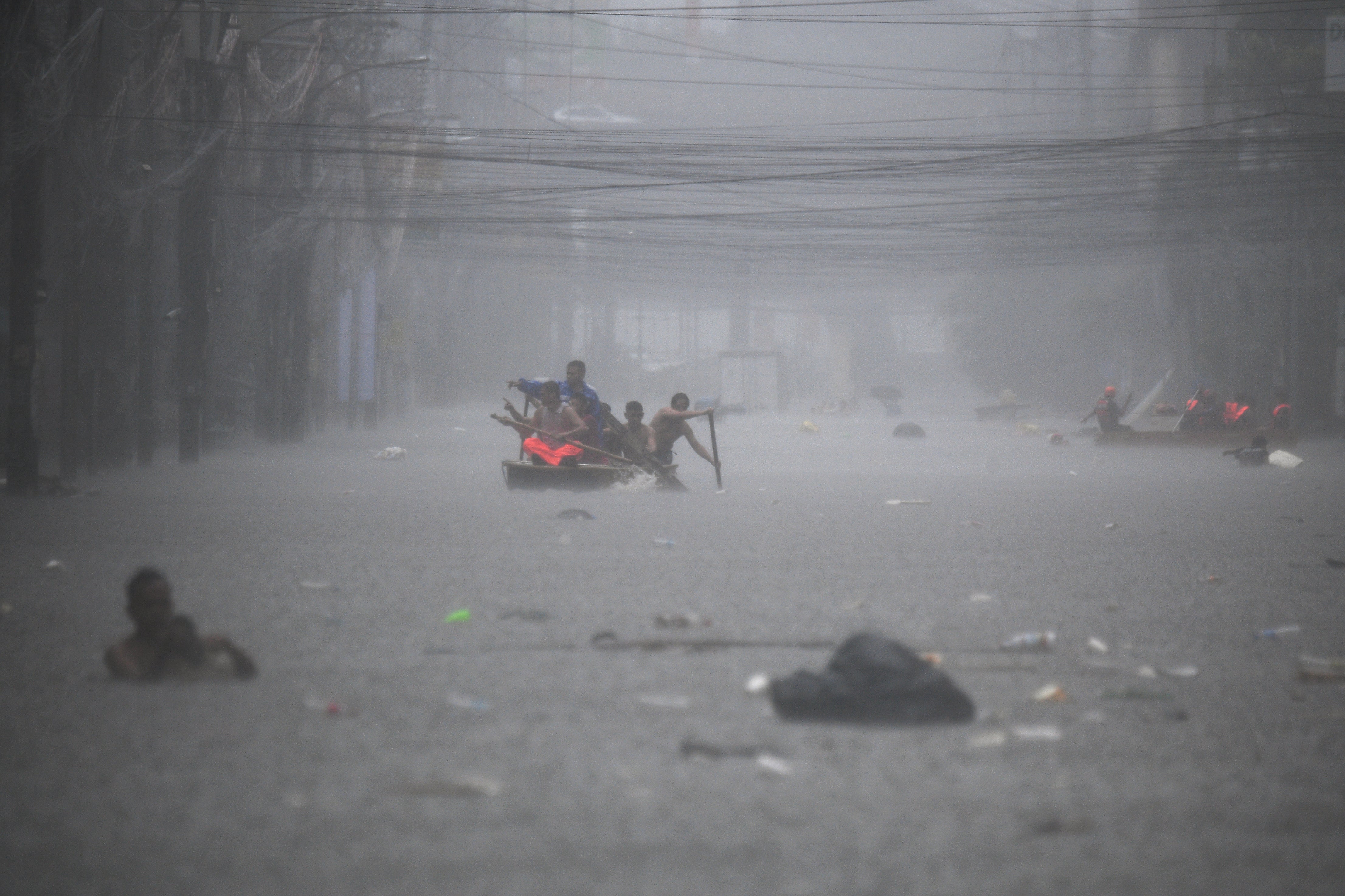 Rescue workers row boats along flooded streets in Manila