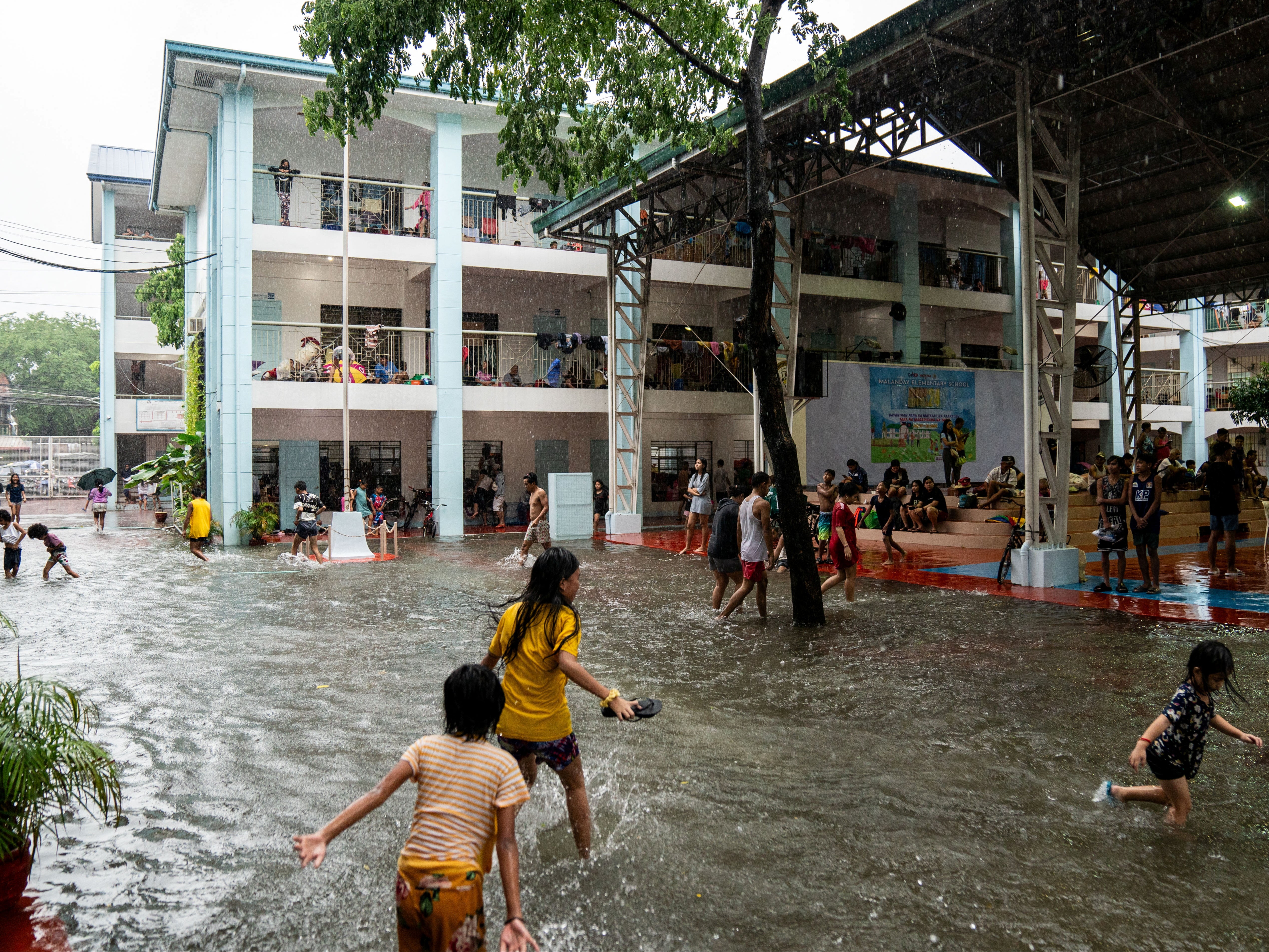 Children play amid flooding at a school temporarily converted into an evacuation centre in Manila