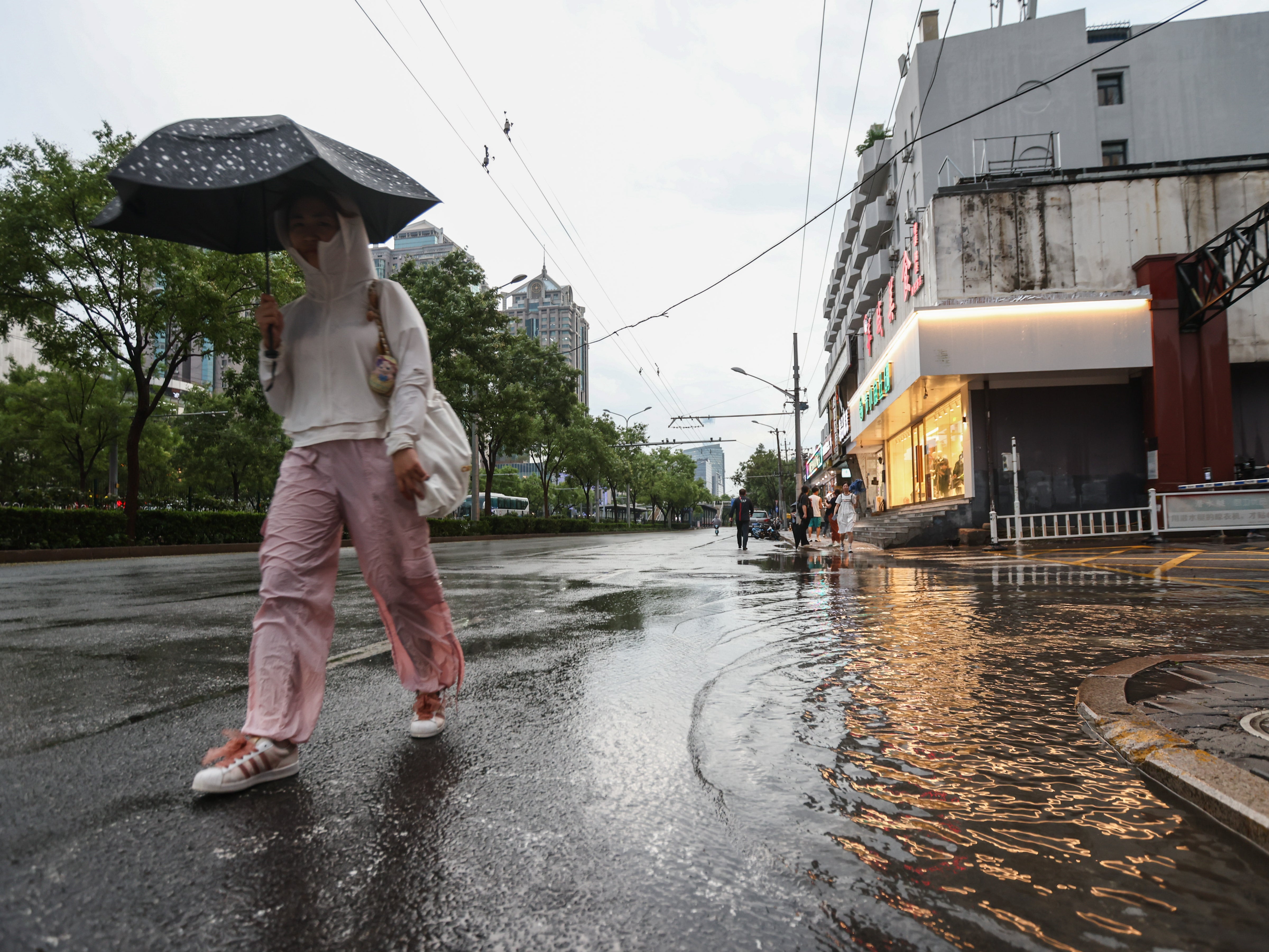 A woman walks with an umbrella during heavy rain, on a street in Beijing, China