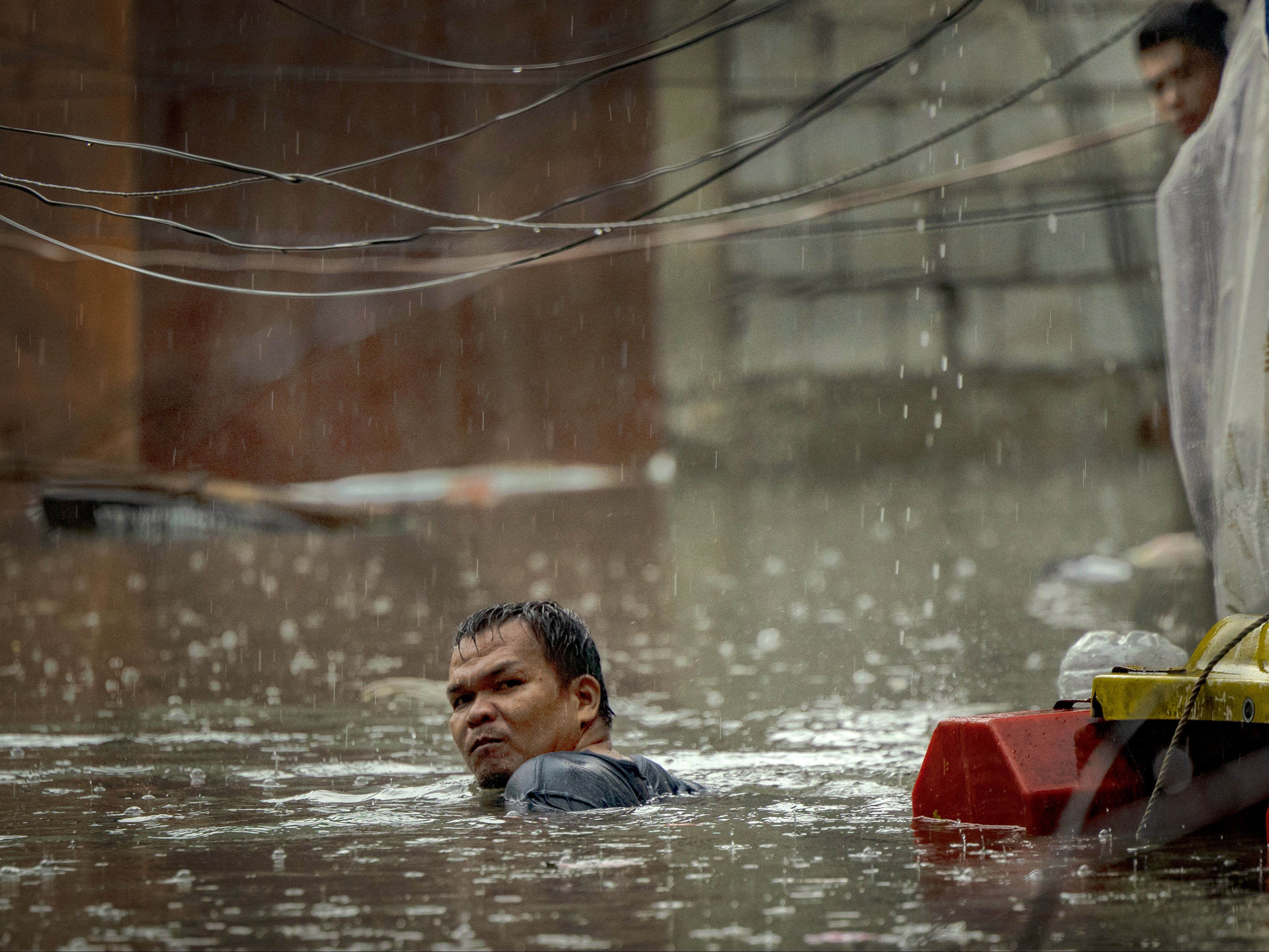 A resident wades floodwaters brought about by Typhoon Gaemi and monsoon rains