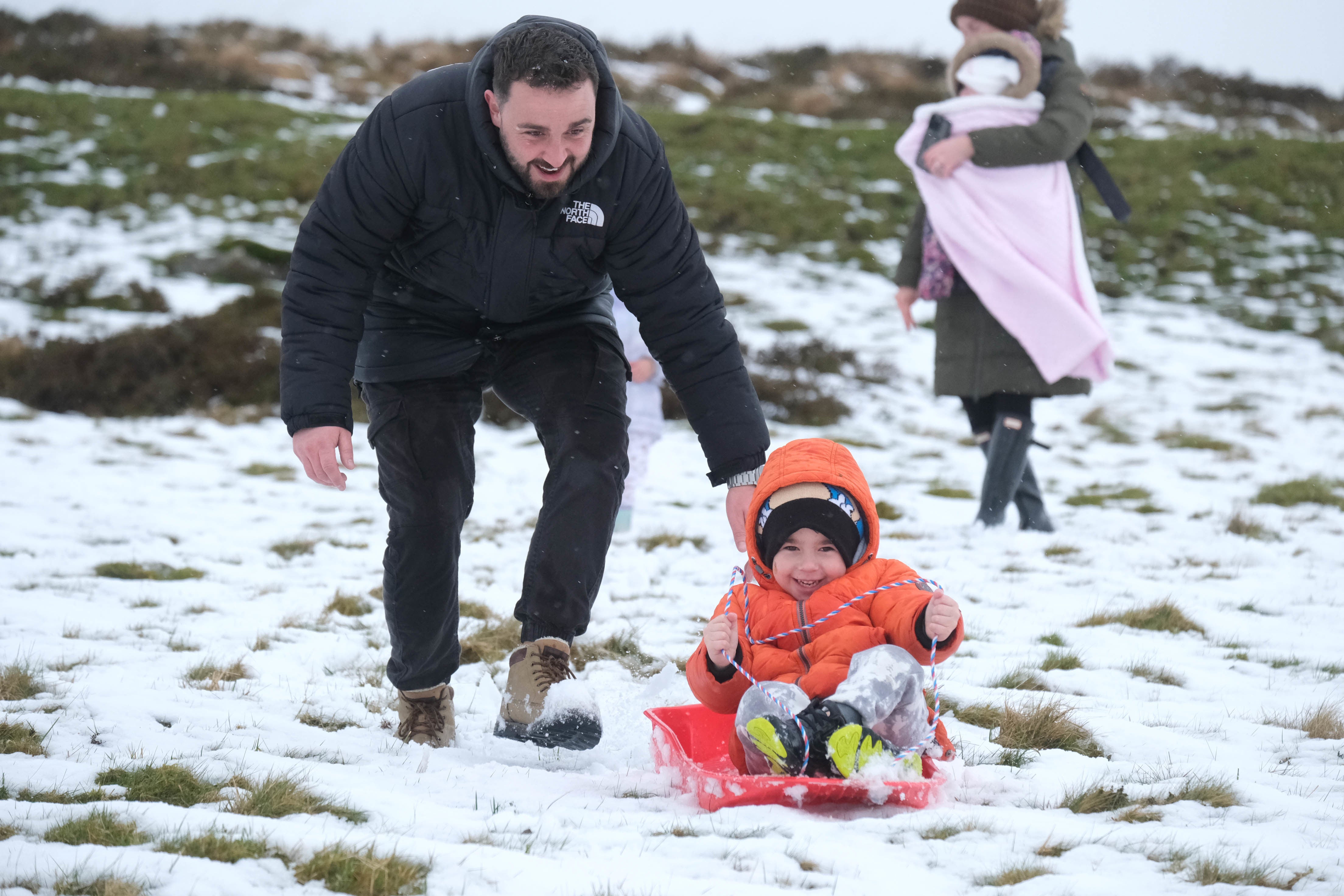 Jack Campbell pushes his son Harvey on a sledge in the snow on Dartmoor in March (Matt Keeble/PA)