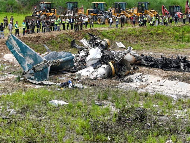 <p>Army personnel and other officials stand around the debris of a Saurya Airlines’ flight after it crashed during takeoff at Tribhuvan International Airport in Kathmandu on 24 July 2024</p>