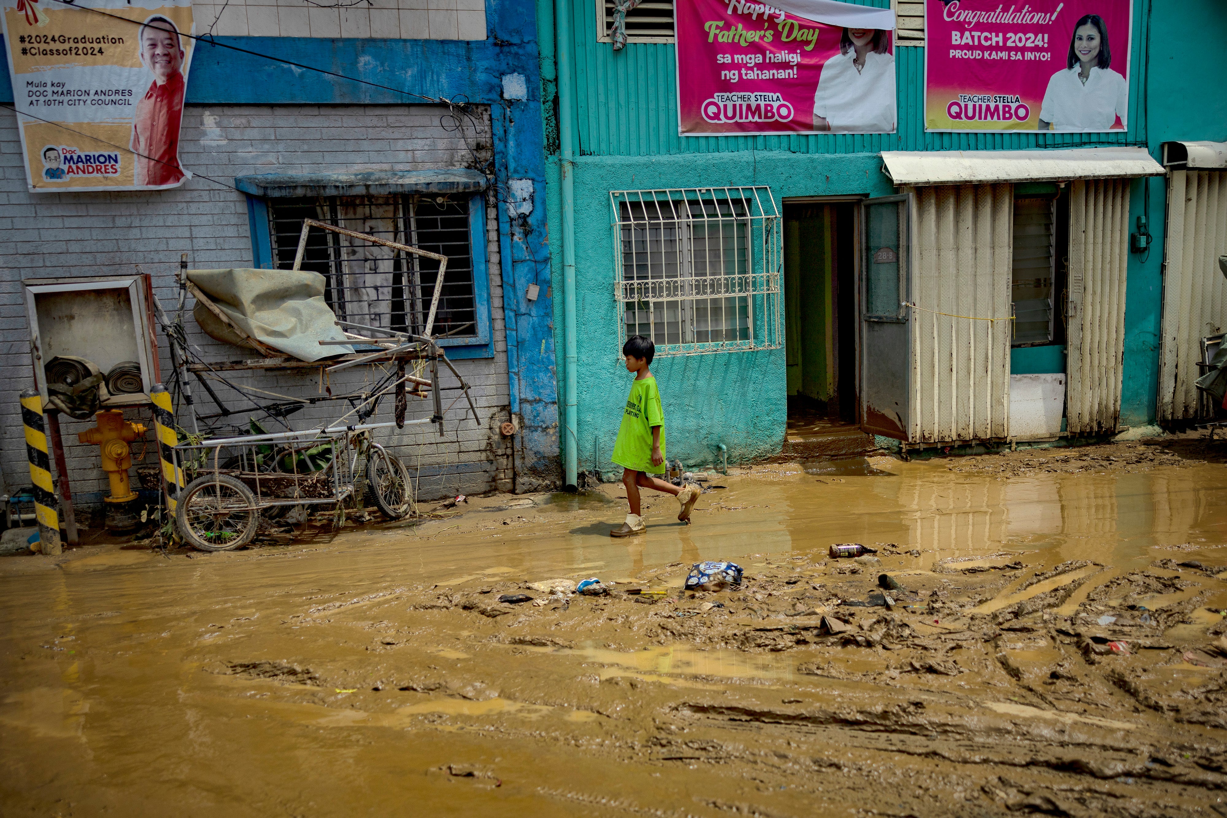 A child walks along a muddied road after it was flooded by Typhoon Gaemi