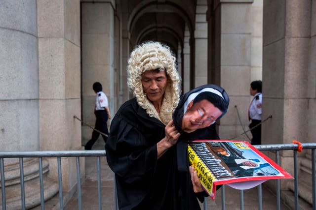 <p>File. A protester dressed as a judge and carrying a mask of Chinese president Xi Jinping stands outside a court after marching in Hong Kong on 20 August 2017</p>