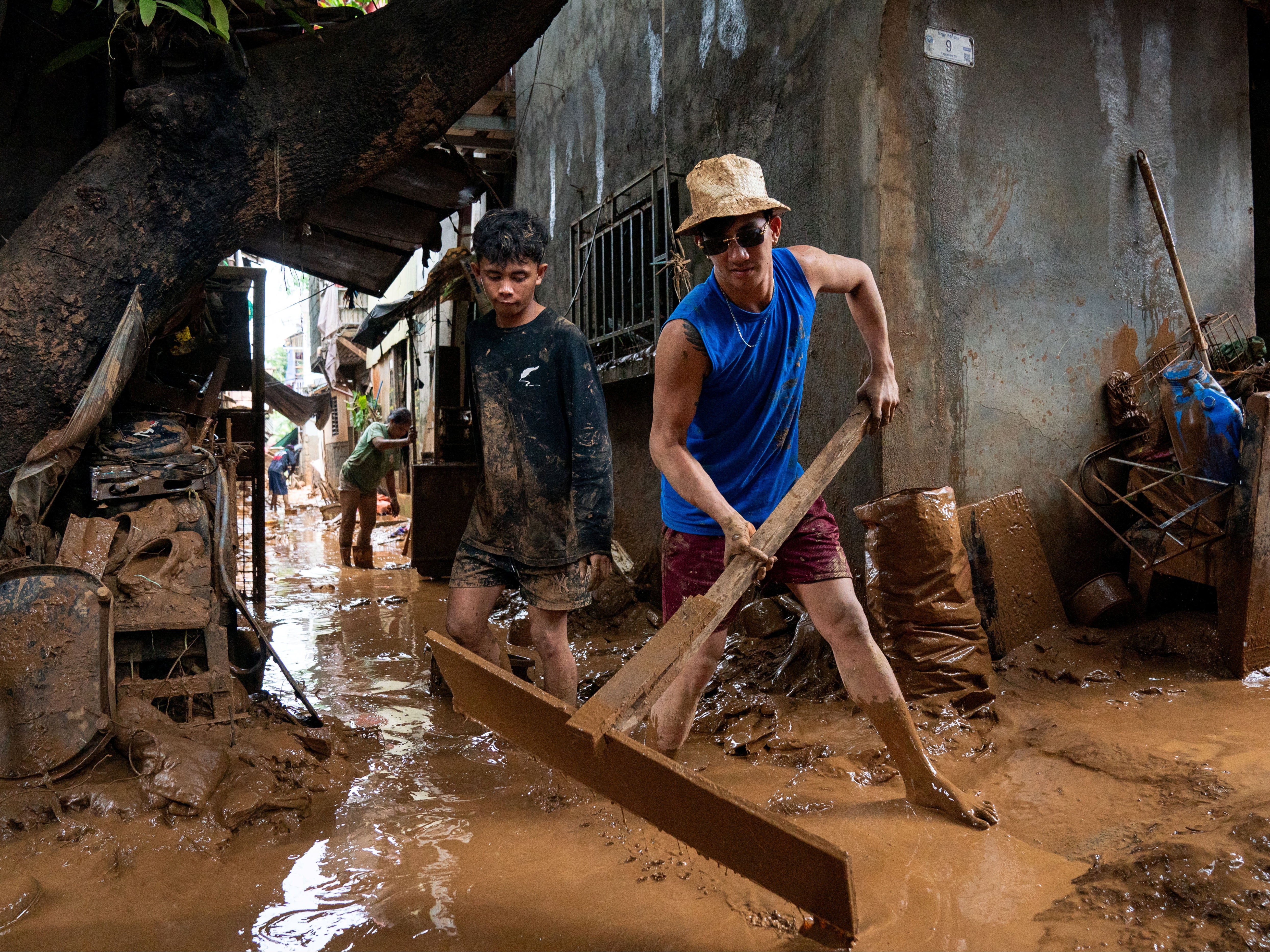 A man sweeps the mud off the alley following the floods brought by Typhoon Gaemi, in San Mateo town, Rizal province, Philippines, 25 July 2024