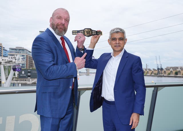 <p>Mayor of London Sadiq Khan, right, holds aloft a gifted mini replica WWE Championship belt, with Paul ‘Triple H’ Levesque</p>