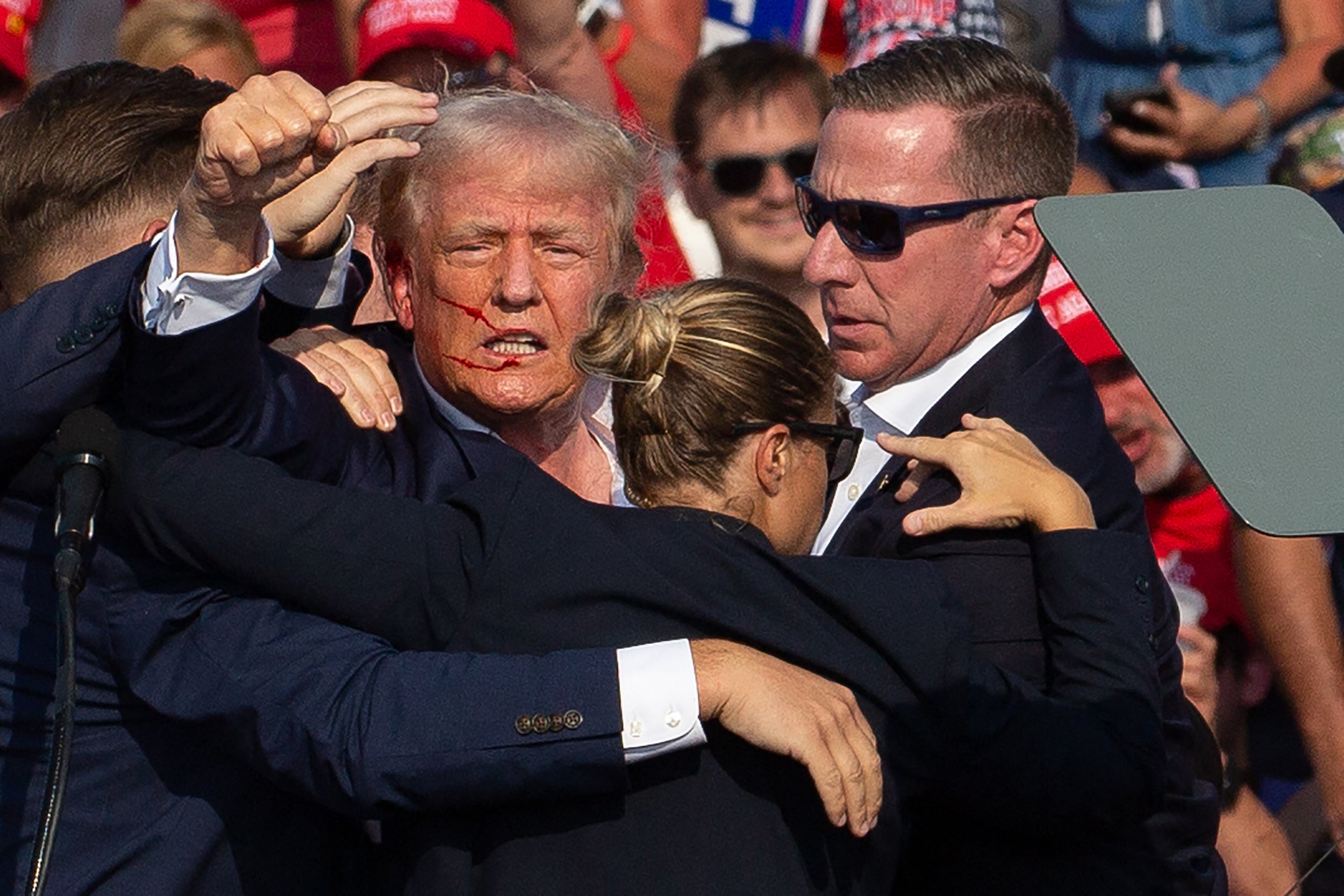 Donald Trump is seen with blood on his face surrounded by secret service agents as he is taken off the stage at a campaign event in Butler