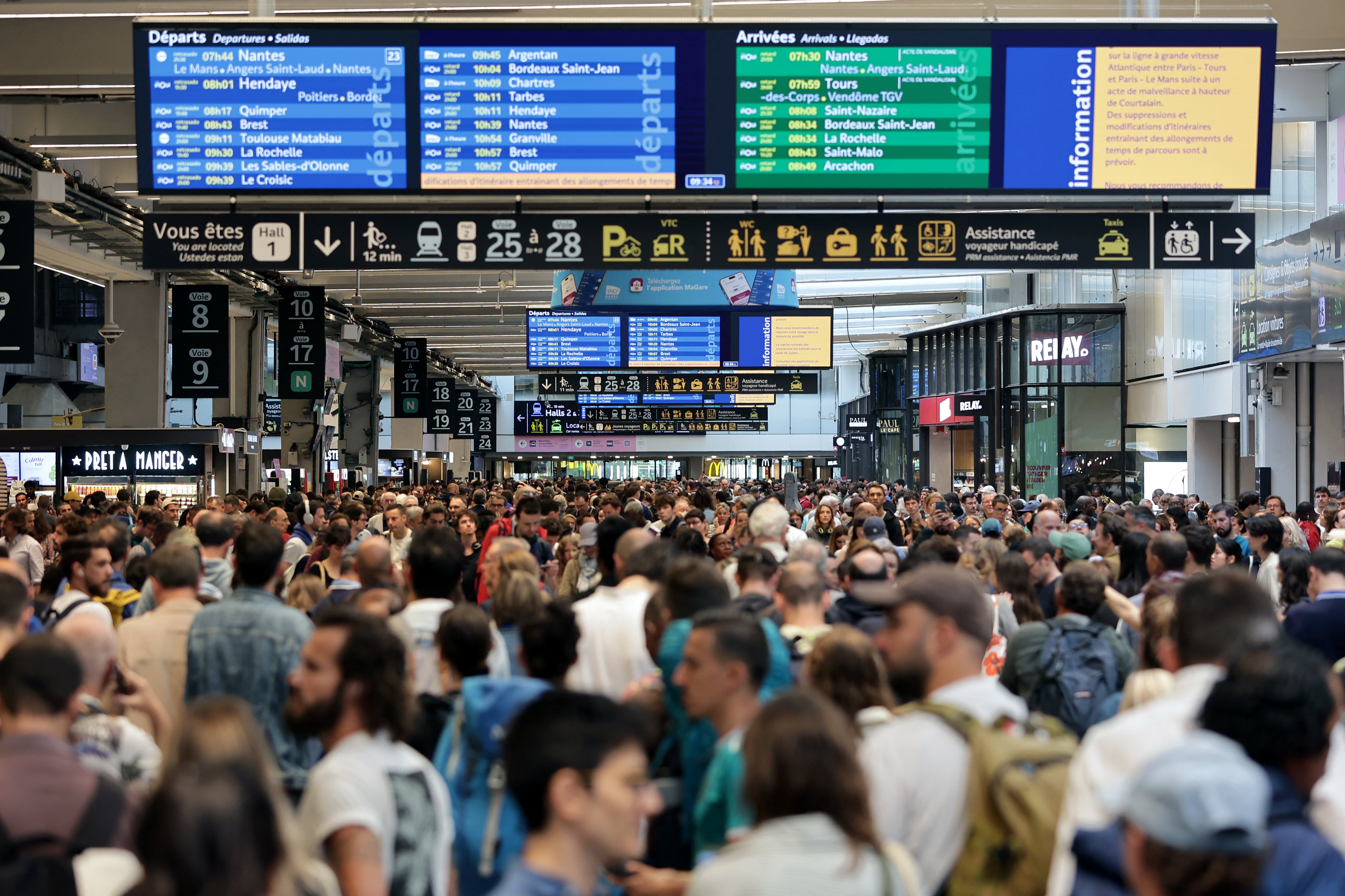 Passengers gather around the departure boards at the Gare Montparnasse train station in Paris on Friday