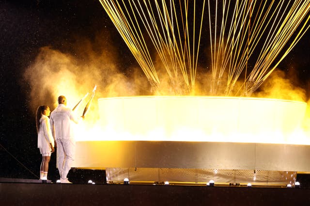 <p>And the Olympic flame is lit by Marie-Jose Perec, left, and Teddy Riner (Jan Woitas/PA)</p>