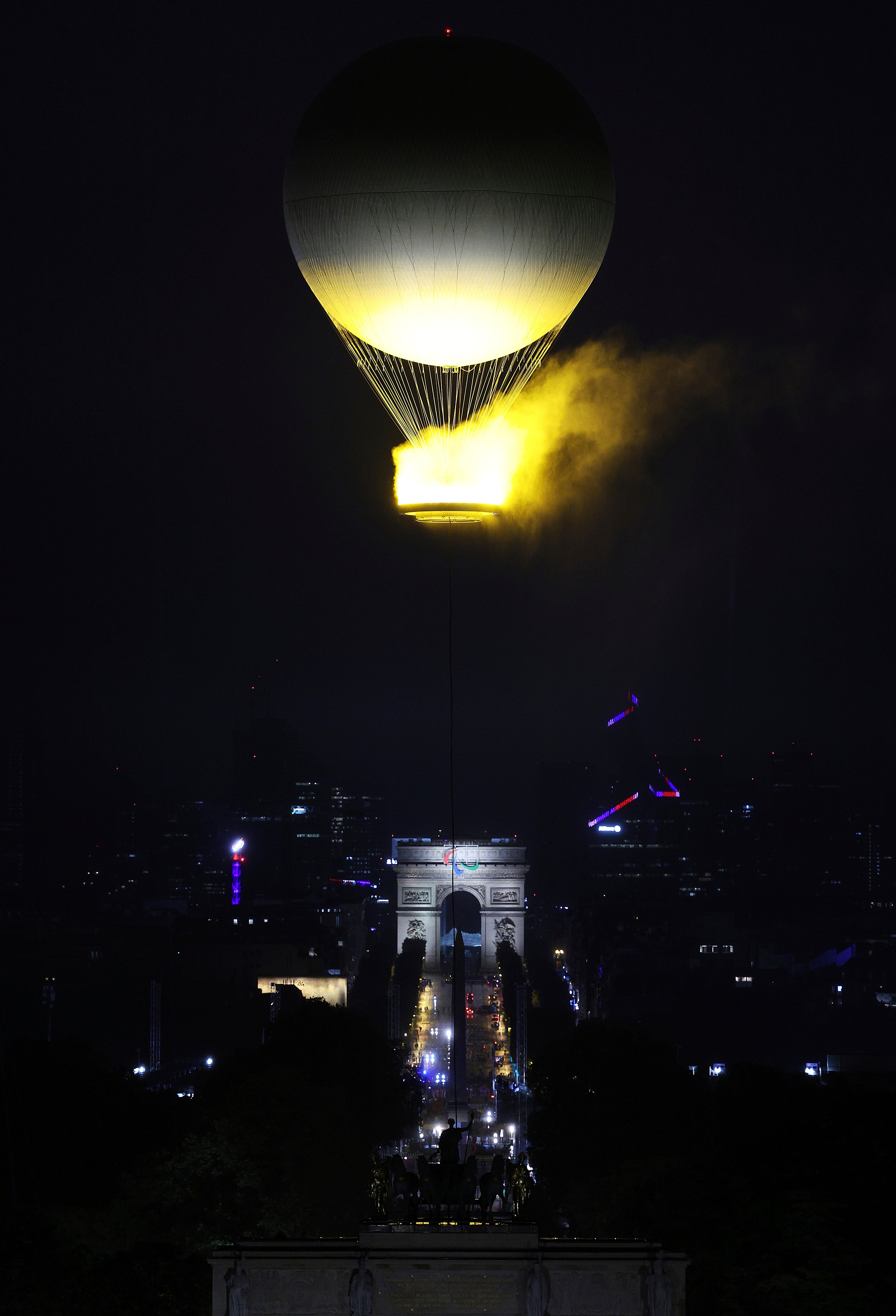 A balloon carrying the Olympic Cauldron rises over the Arc de Triomphe (Richard Heathcote/Pool Photo via AP)