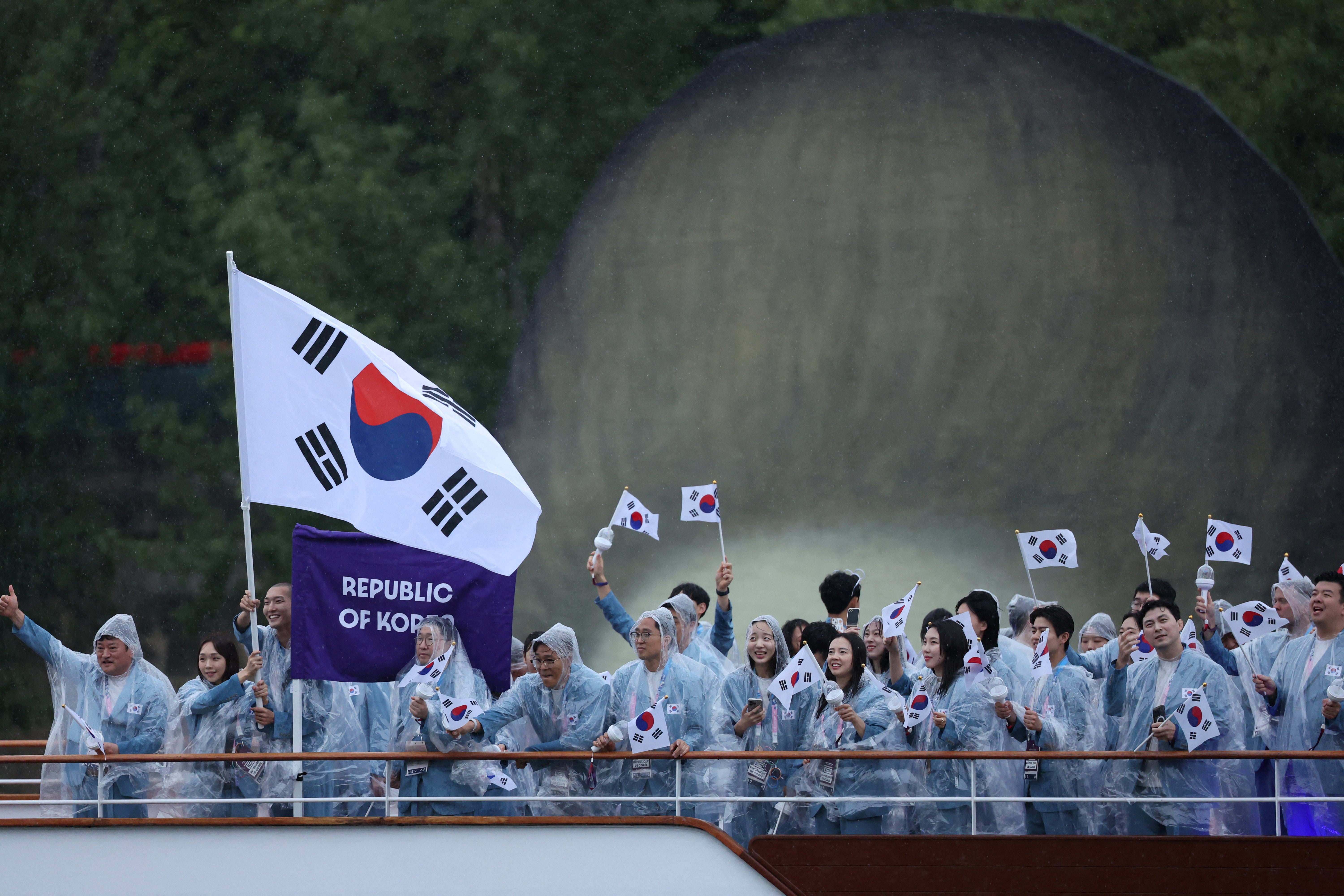 Athletes of South Korea aboard a boat in the floating parade on the river Seine during the opening ceremony